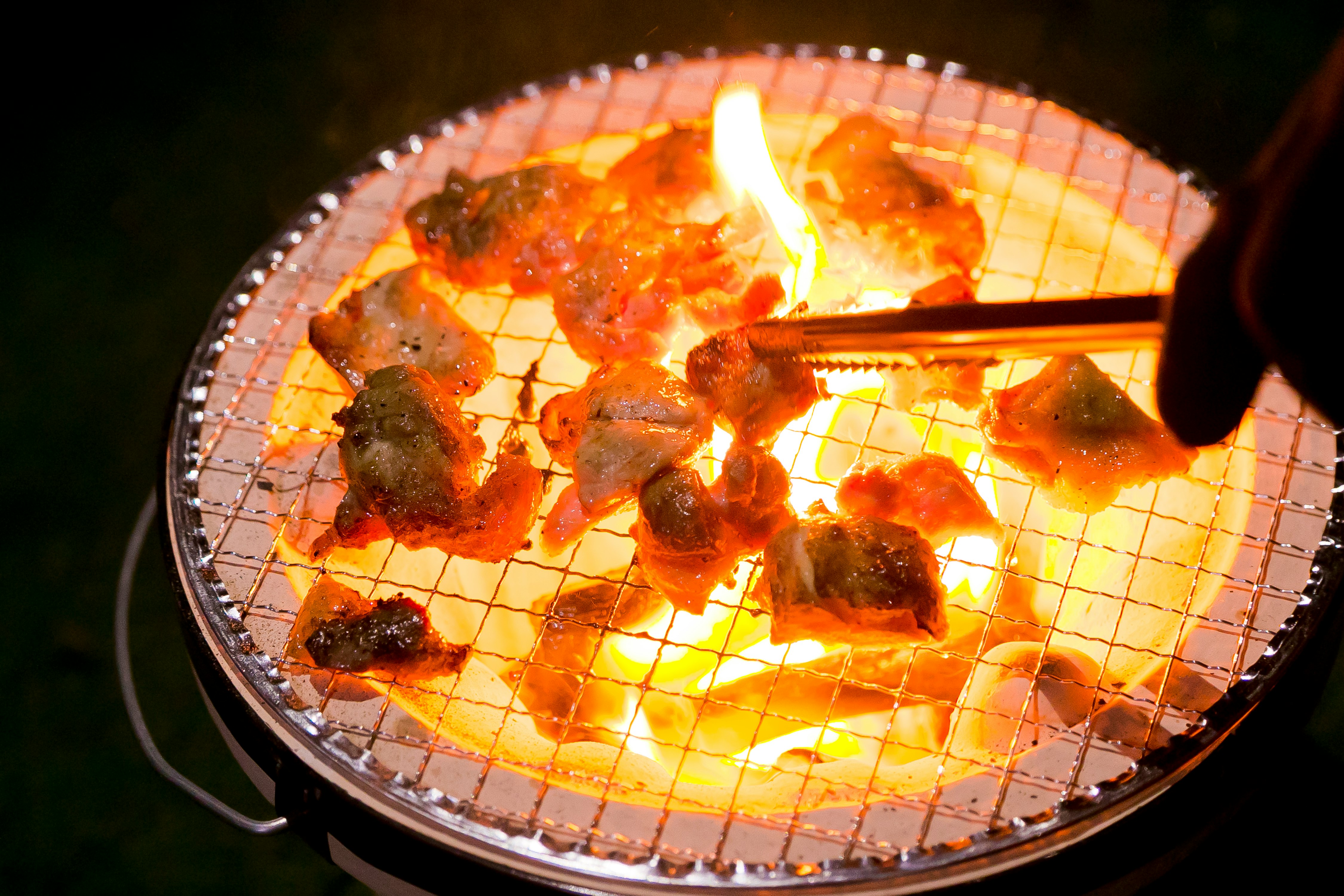 網焼きの上で炎が上がる肉料理の鉄板