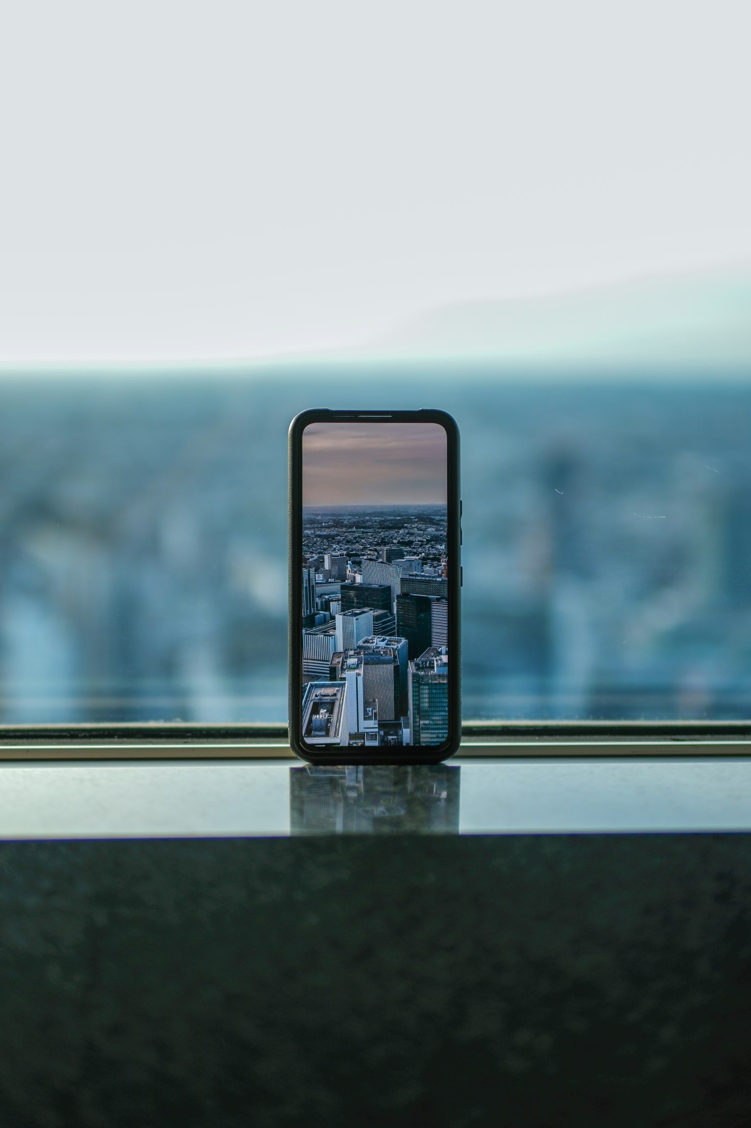 Smartphone posato vicino a una finestra che mostra un paesaggio urbano