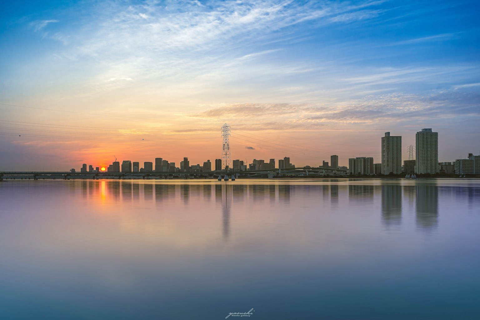 Ligne d'horizon de la ville au coucher du soleil avec des reflets sur l'eau