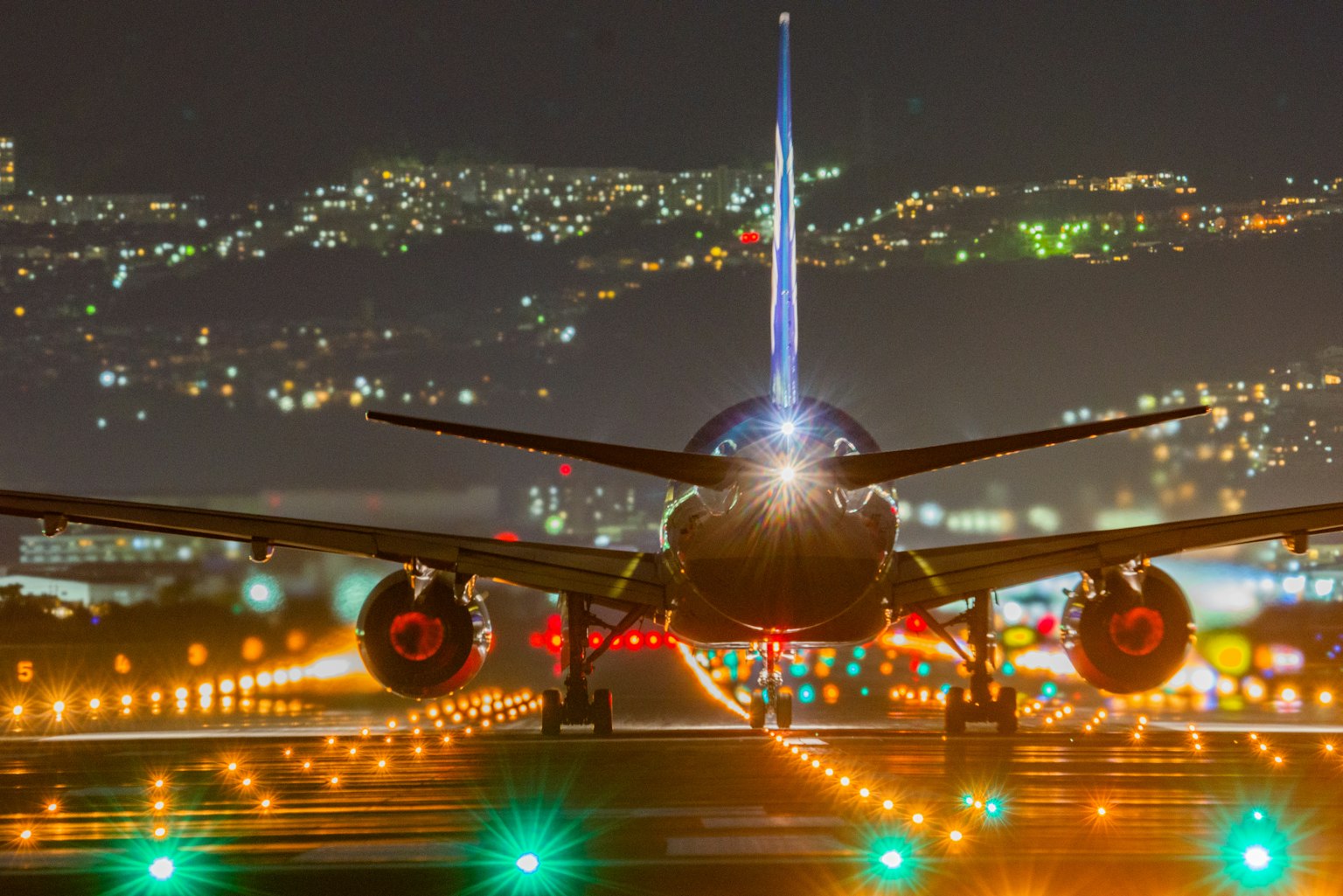 Aereo sulla pista di notte con luci della città sullo sfondo