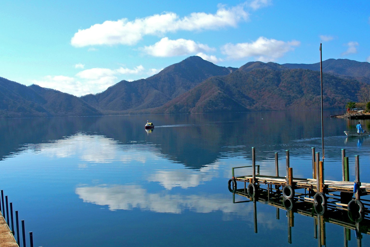 Vista serena del lago con una barca e riflessi delle montagne