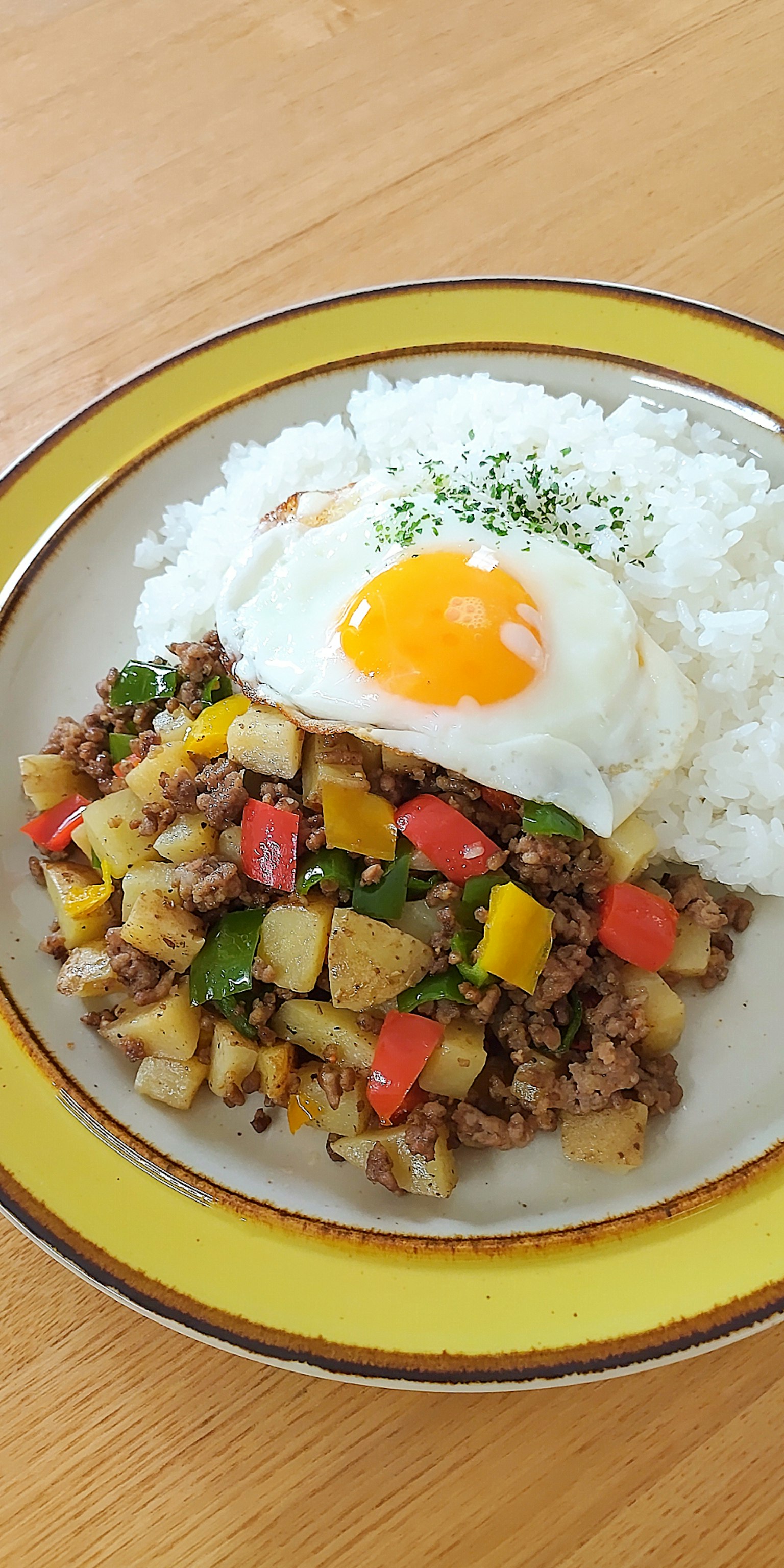 Une assiette de riz surmontée d'un œuf au plat et d'un mélange de légumes et de viande hachée