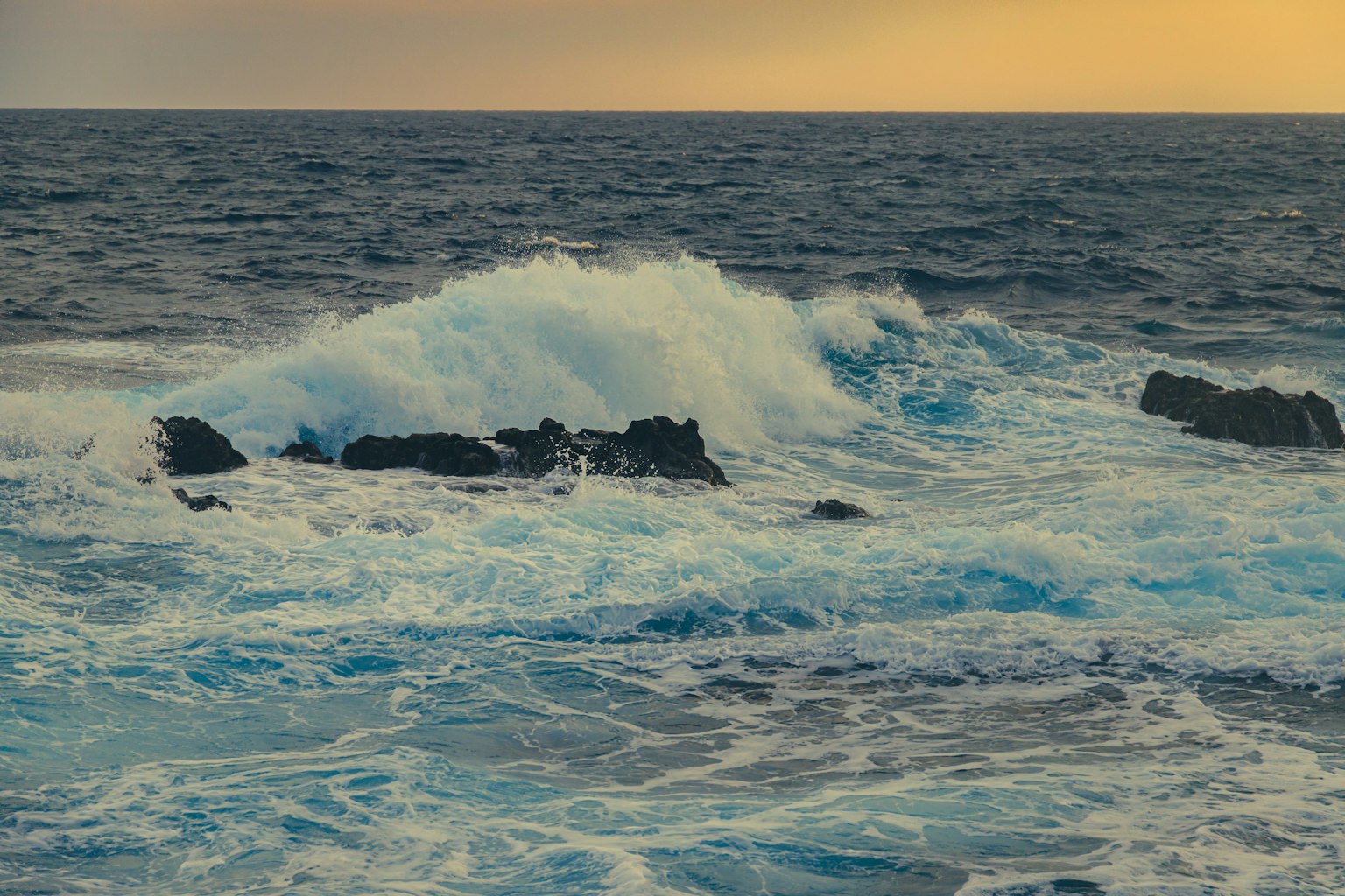 Olas del océano rompiendo contra las rocas durante el atardecer