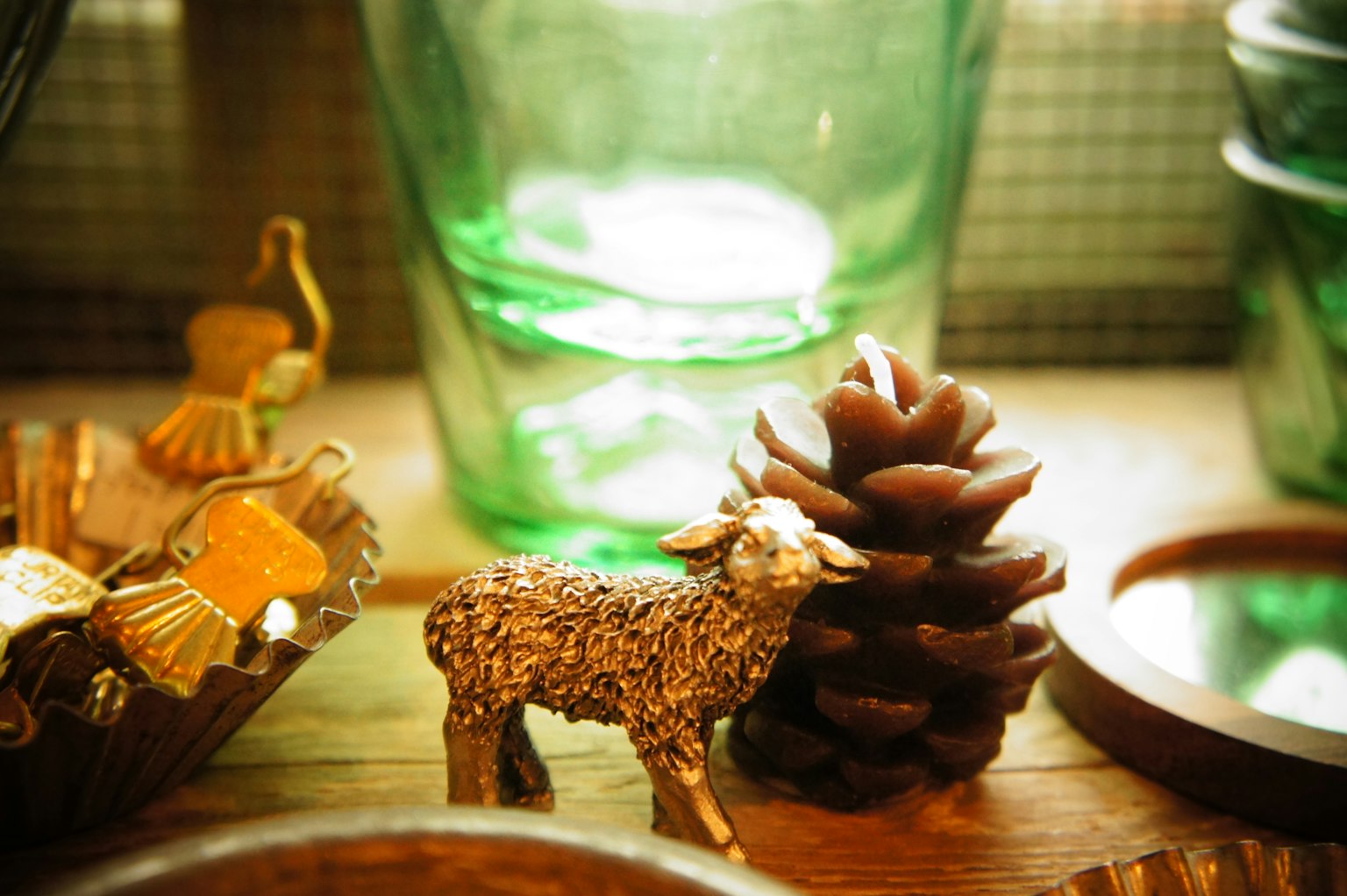 Kleine Schaf-Figur neben einem Tannenzapfen und grünen Glasgefäßen