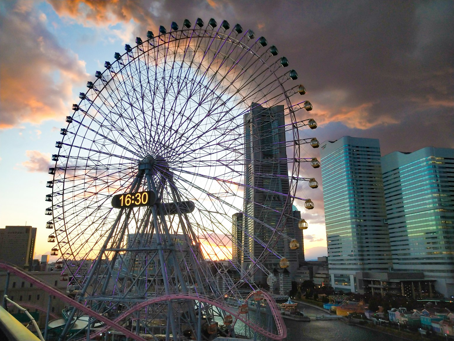 Grande roue avec un magnifique ciel de coucher de soleil et des gratte-ciels modernes en arrière-plan
