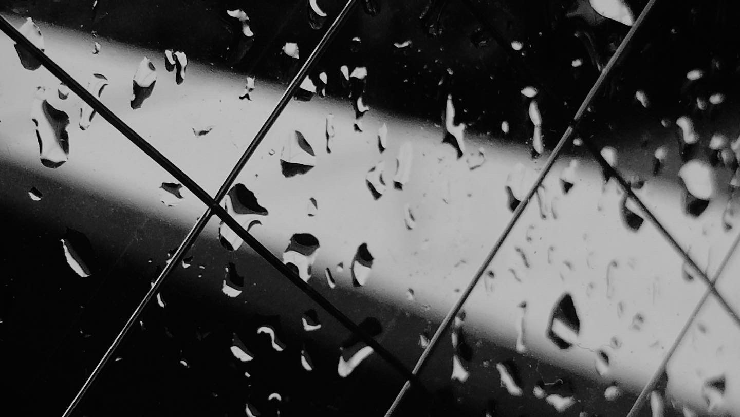 雨粒が付いたガラスと交差する金属フレーム