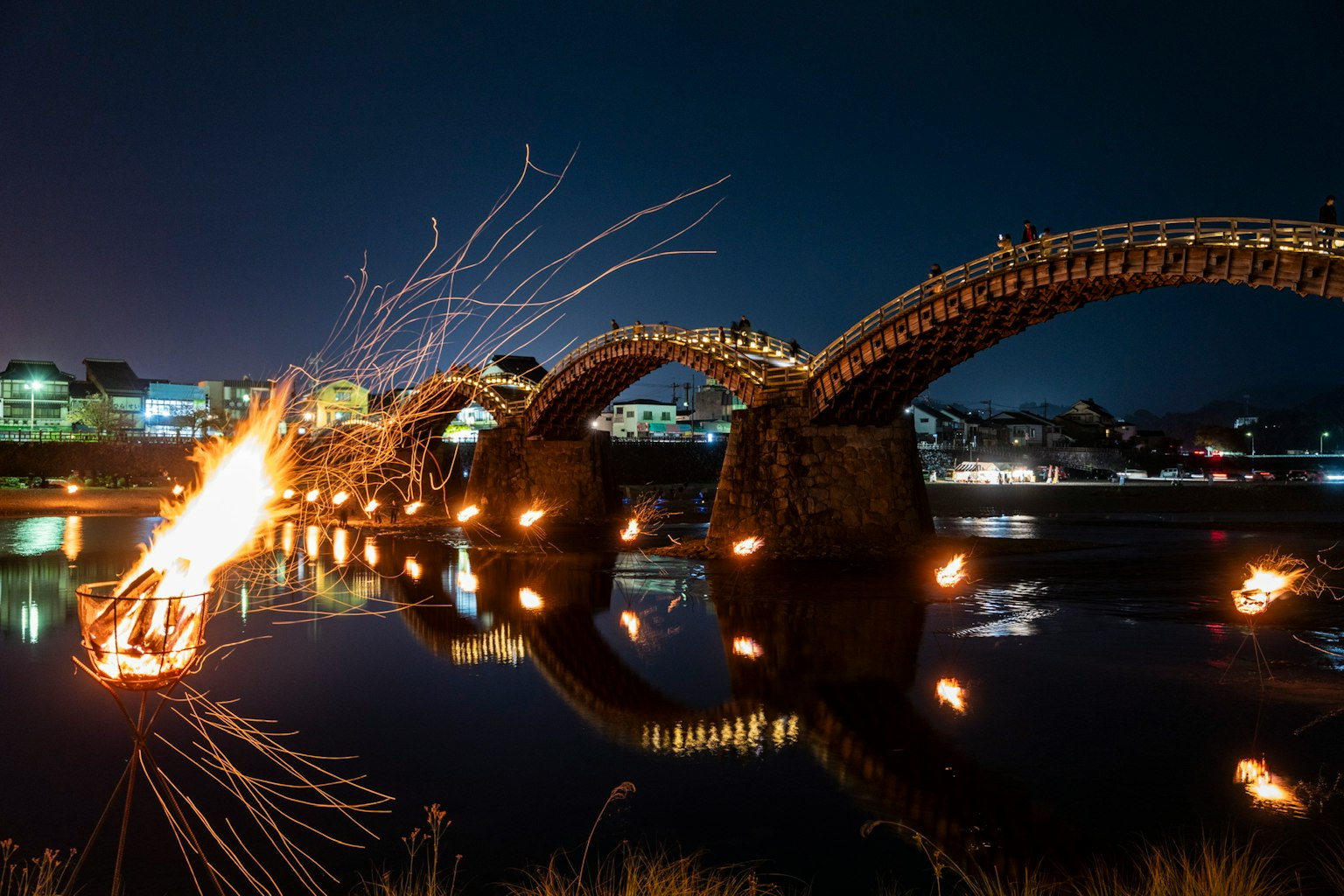 夜の中で美しく照らされた橋と川の景色 火の演出が印象的