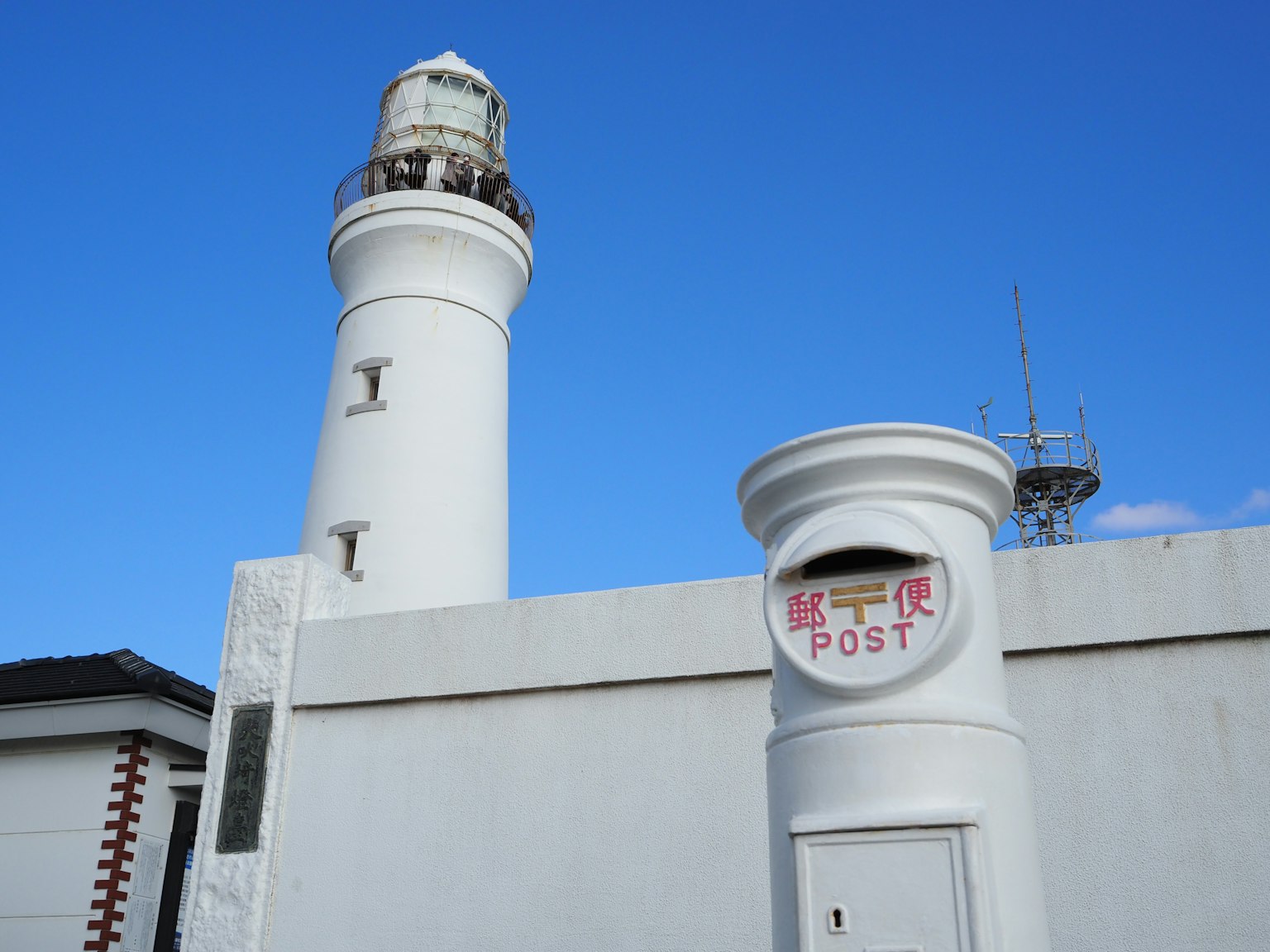 Phare blanc et boîte aux lettres sous un ciel bleu