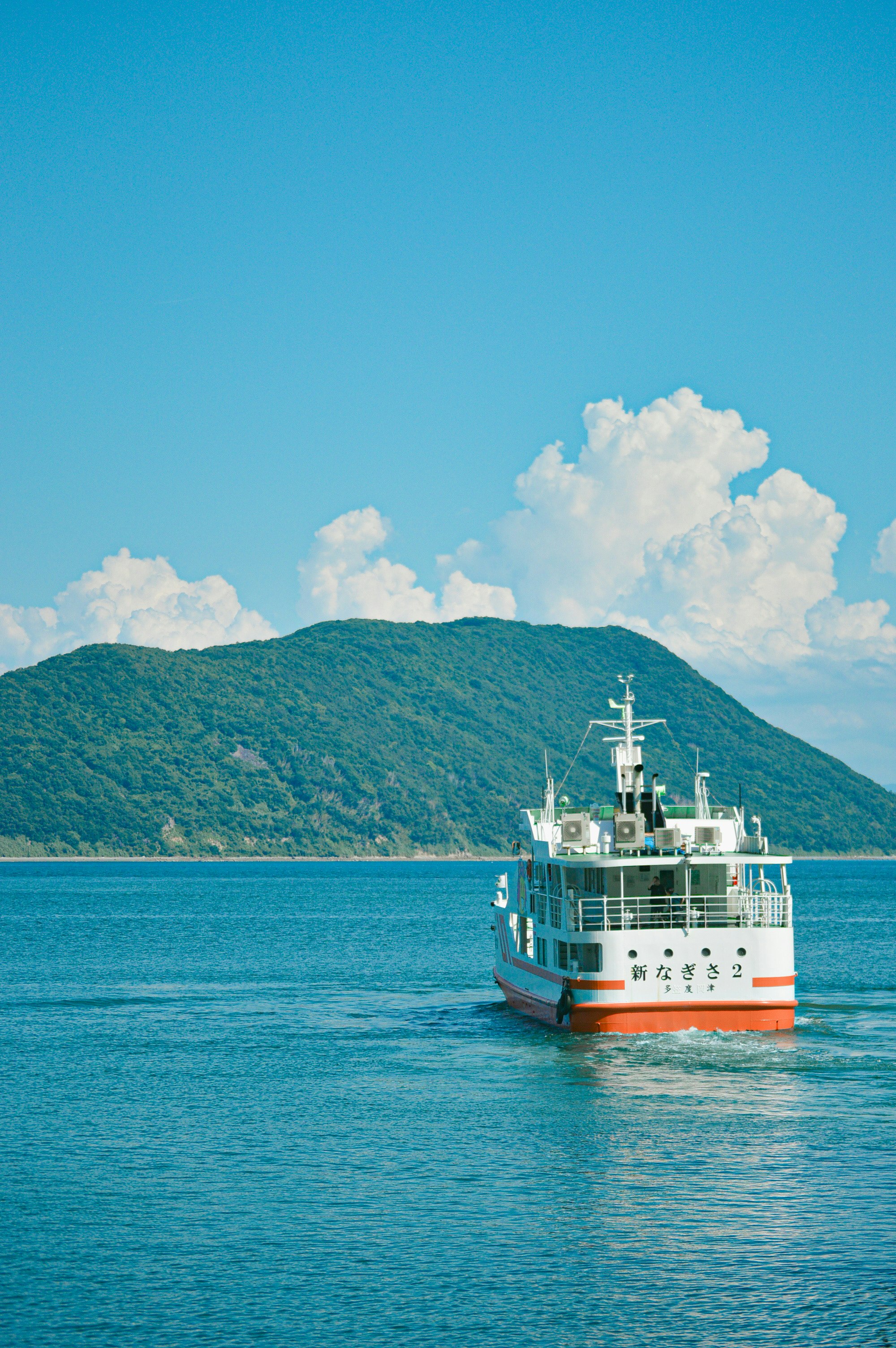 青い海と緑の山を背景に進む船のある風景