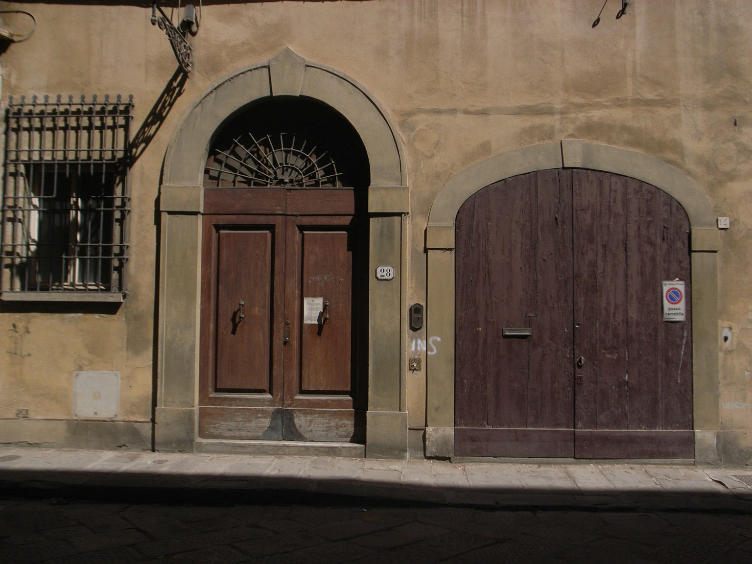 Due porte in legno e una finestra ad arco sull'esterno di un vecchio edificio