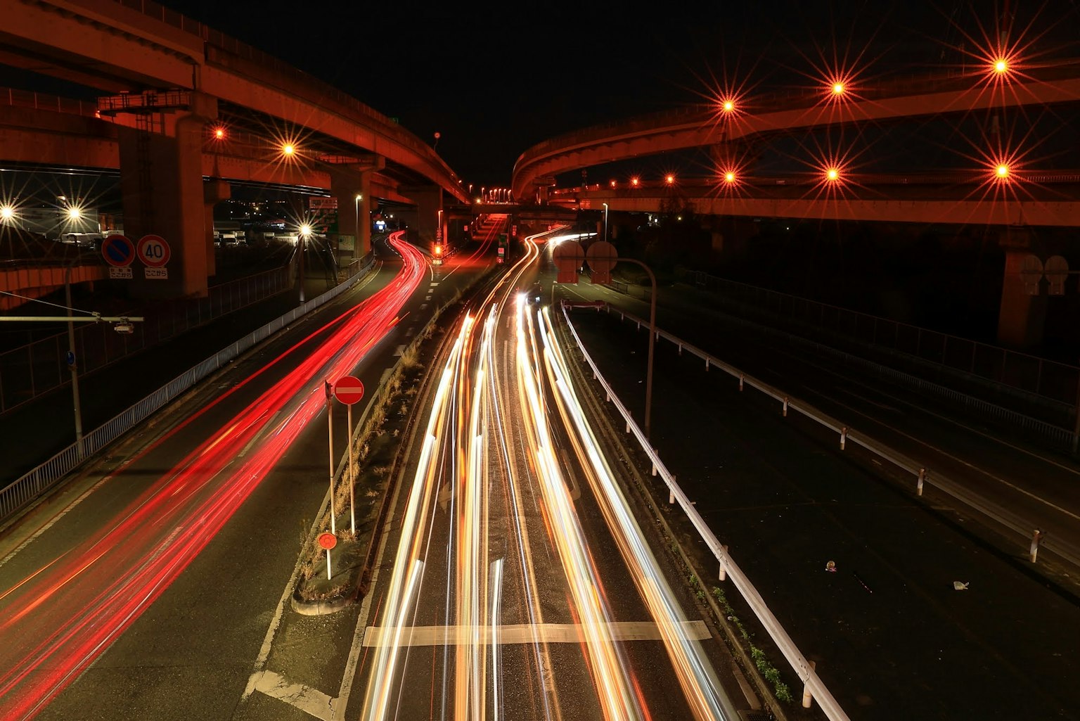 Autostrada notturna con scie di luce e viadotti illuminati