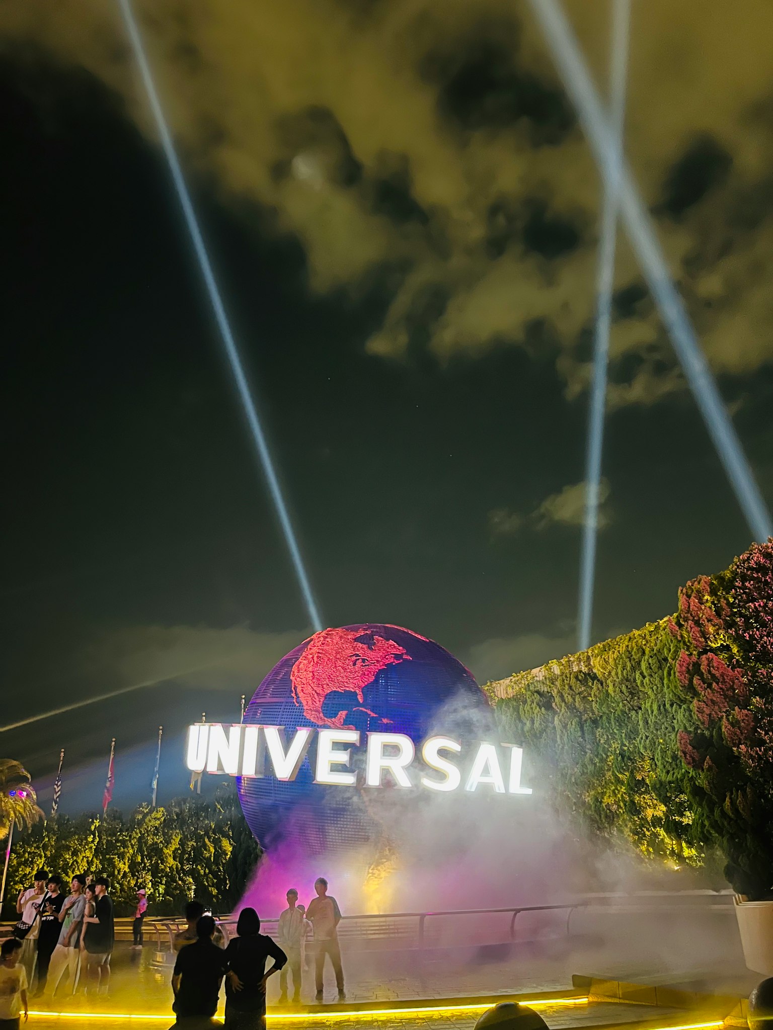 People standing in front of a globe featuring the Universal logo night lighting effects highlighted