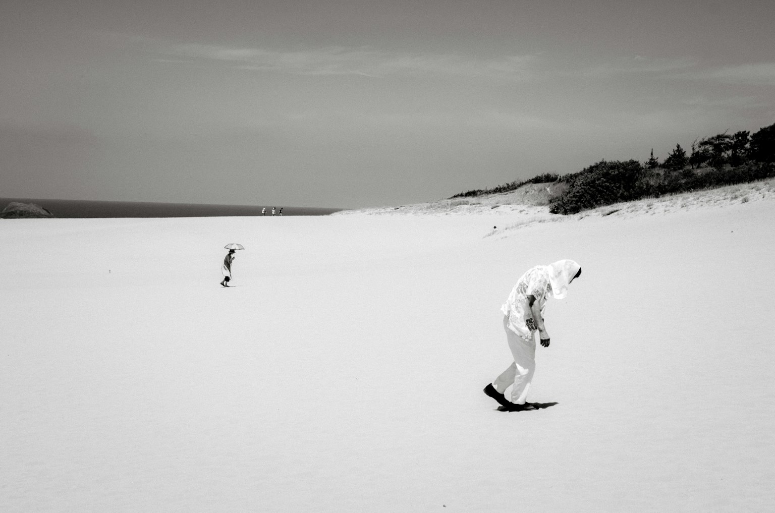 Due figure che camminano su una spiaggia in bianco e nero