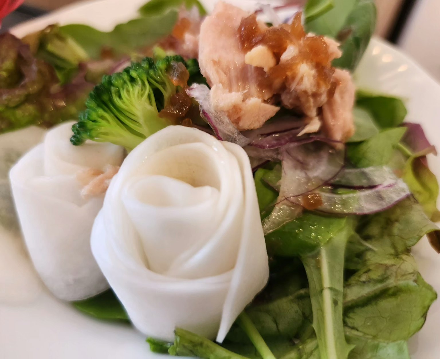 Involtini bianchi a forma di rosa serviti su un letto di verdure