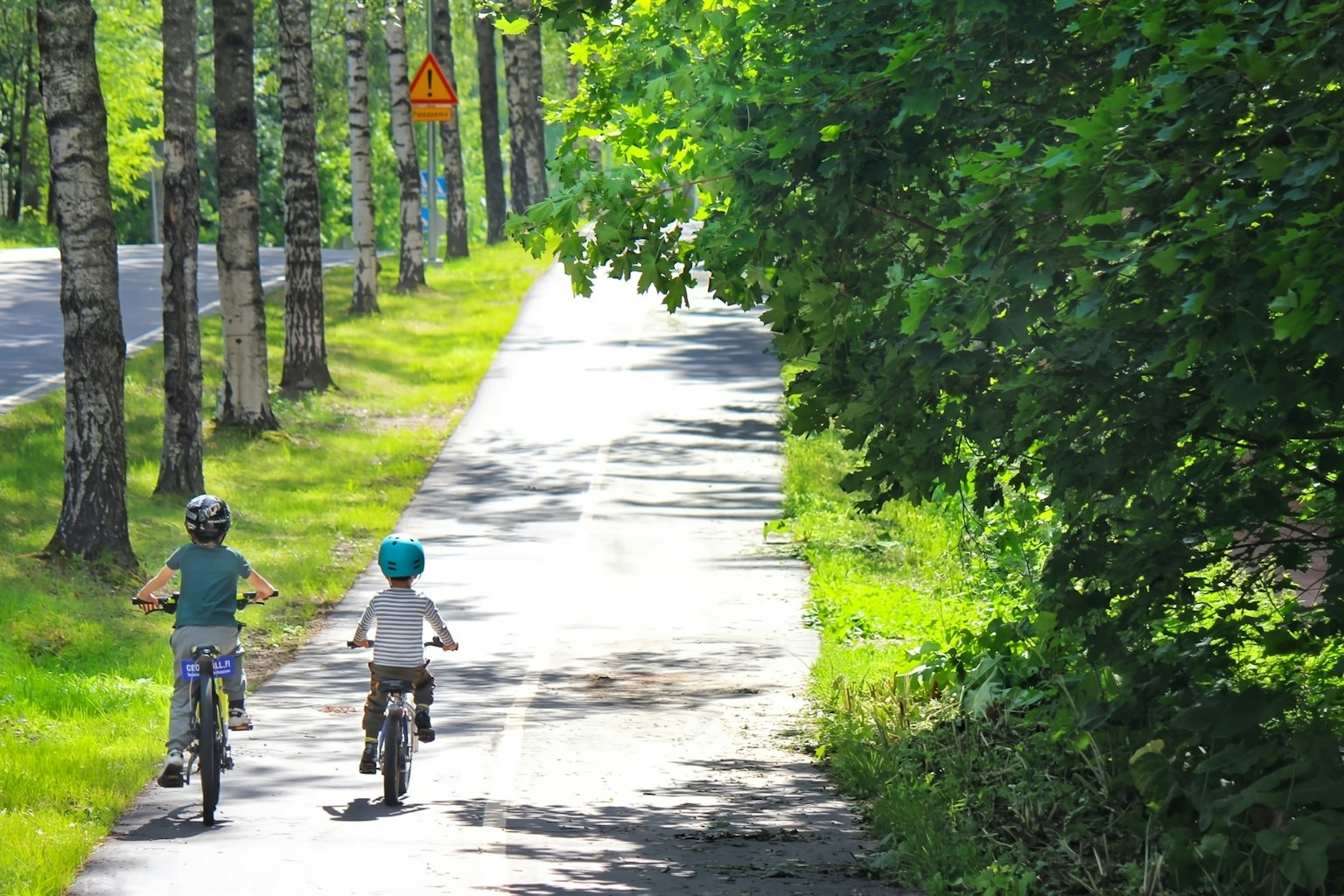 Due bambini in bicicletta su un sentiero alberato