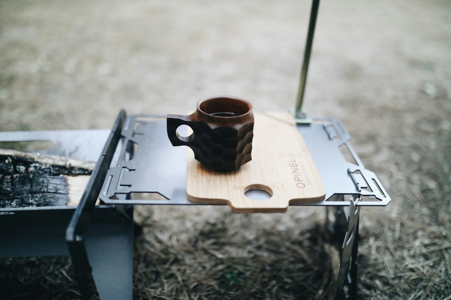 Piring kayu dengan cangkir kopi di atas meja camping