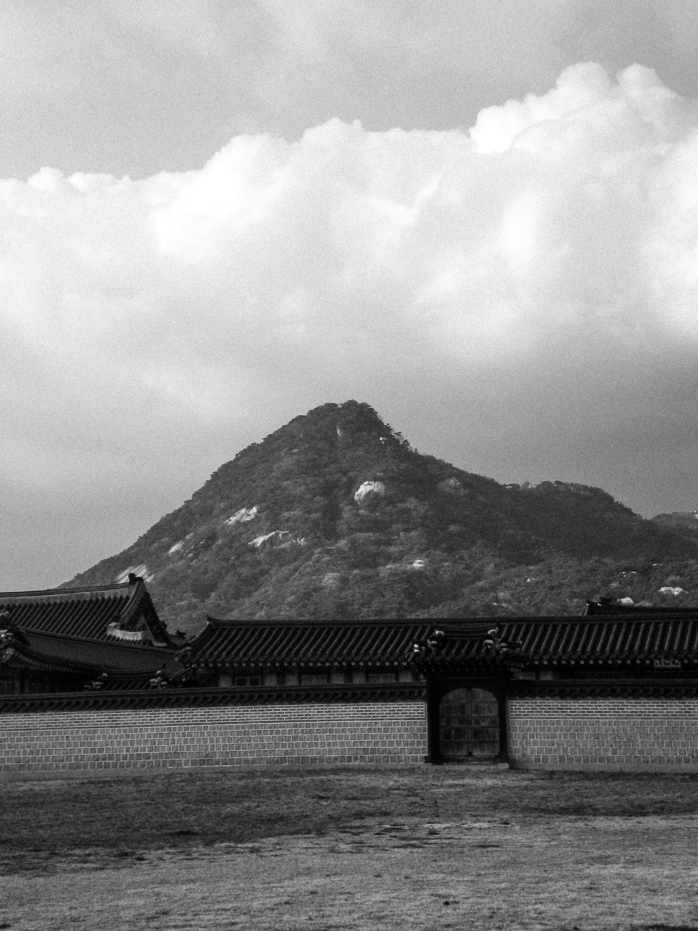 Cour intérieure du palais Gyeongbokgung avec un mur et des bâtiments, et une montagne en arrière-plan