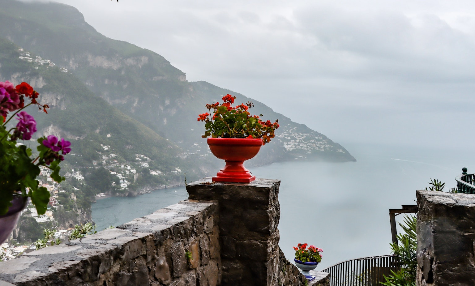 Malersicher Blick auf eine Küstenlandschaft in Italien mit bunten Blumentöpfen und dem Meer