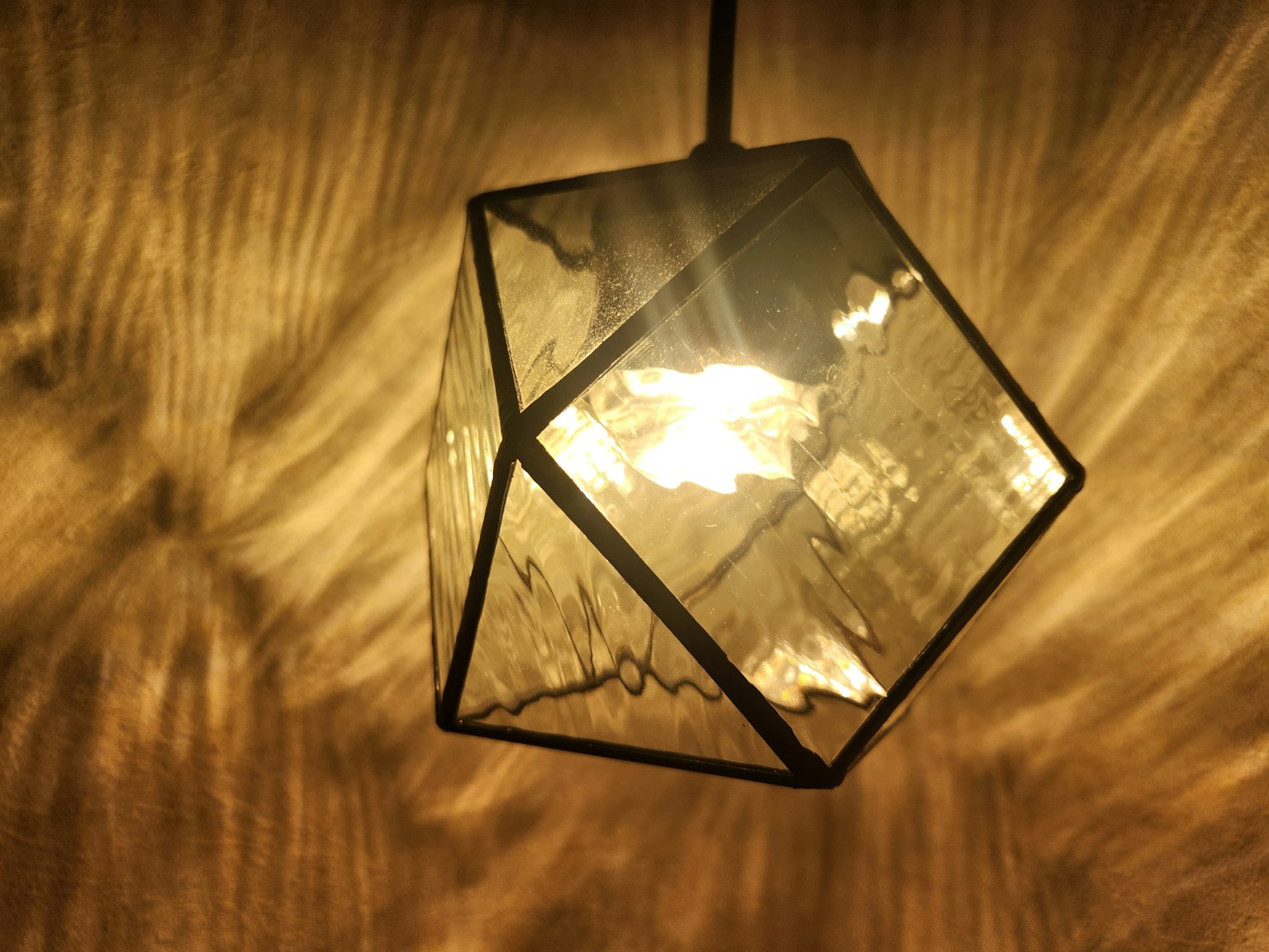 Une belle lampe suspendue émettant une lumière chaude créant des motifs uniques en arrière-plan