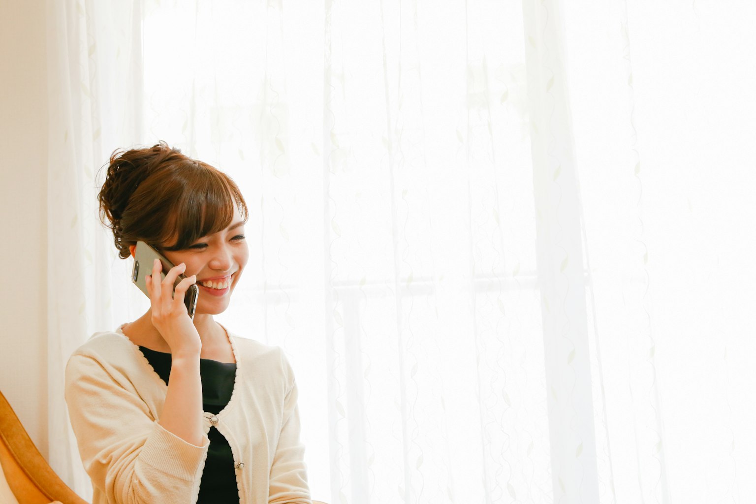 Frau am Telefon lächelnd in einem hellen Innenraum
