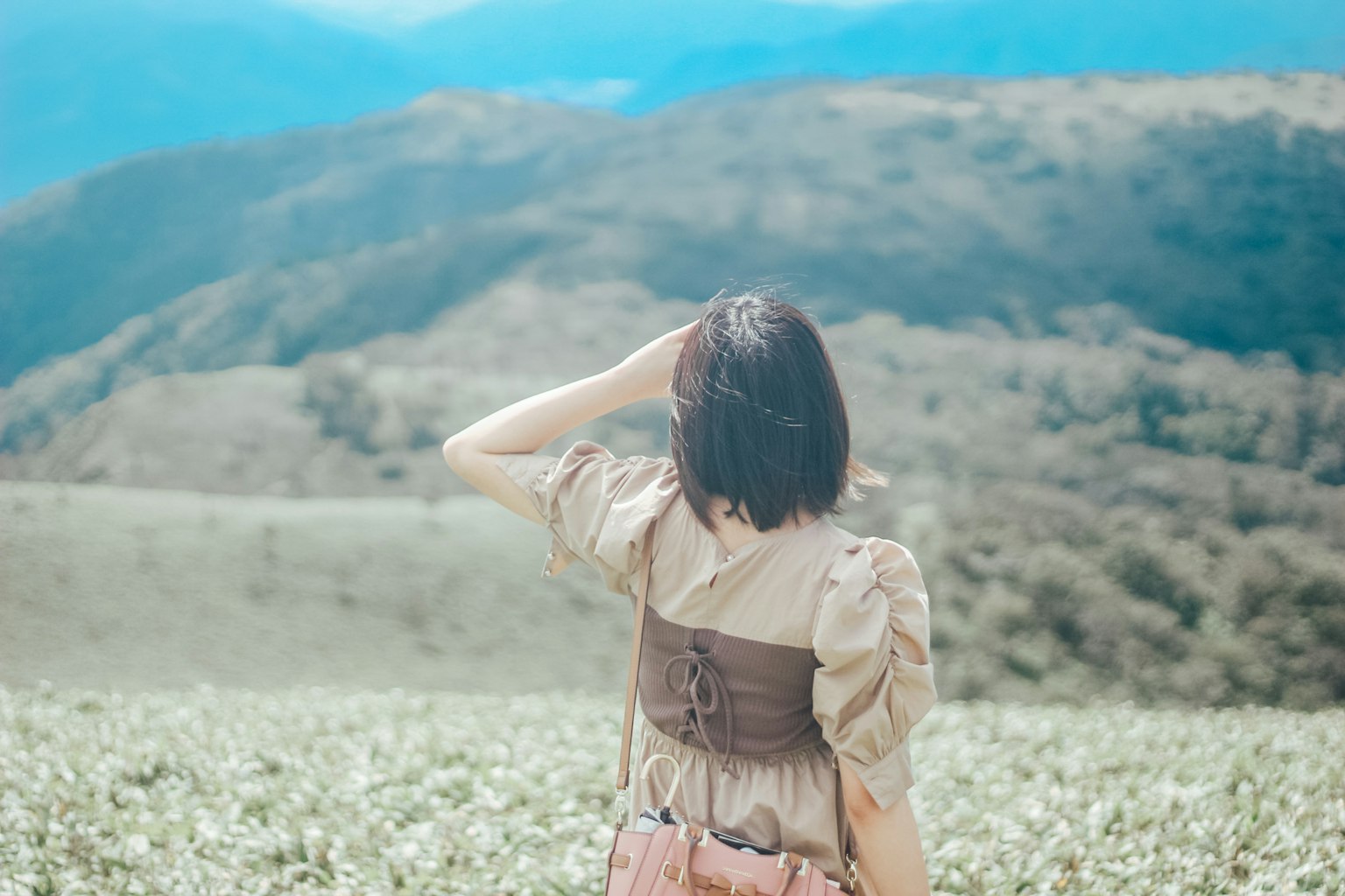 Một người phụ nữ nhìn từ phía sau nhìn về những ngọn đồi xanh