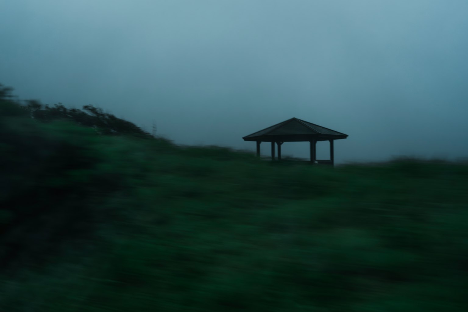 Un gazebo en un paisaje brumoso con hierba verde