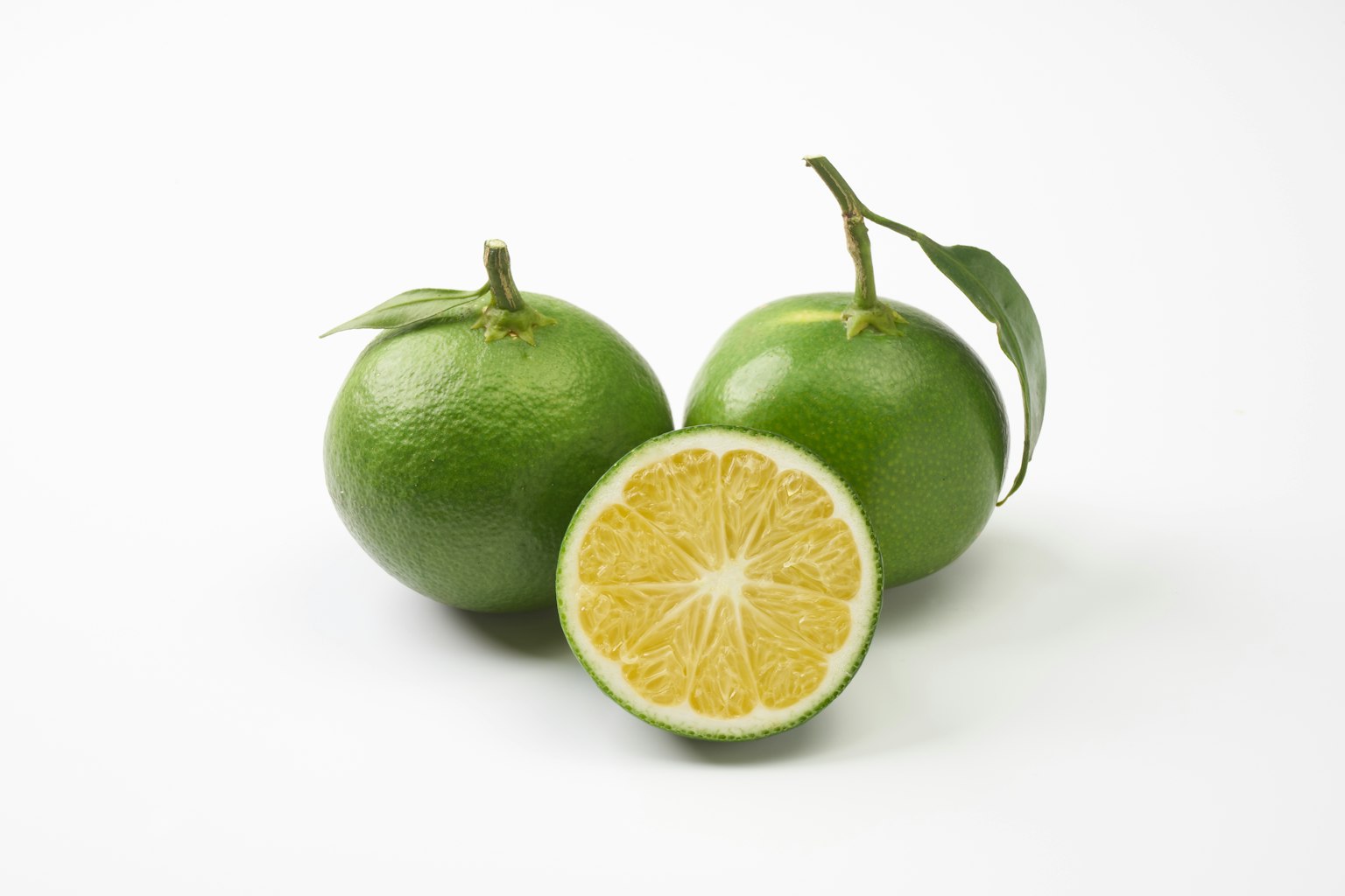 Grüne Orangen mit einer Schnittfläche, die das gelbe Fruchtfleisch zeigt