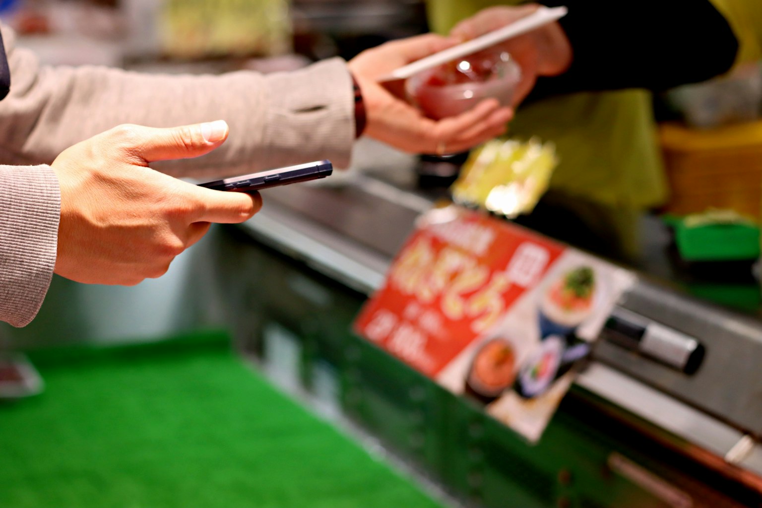 Une personne tenant un smartphone recevant de la nourriture au comptoir