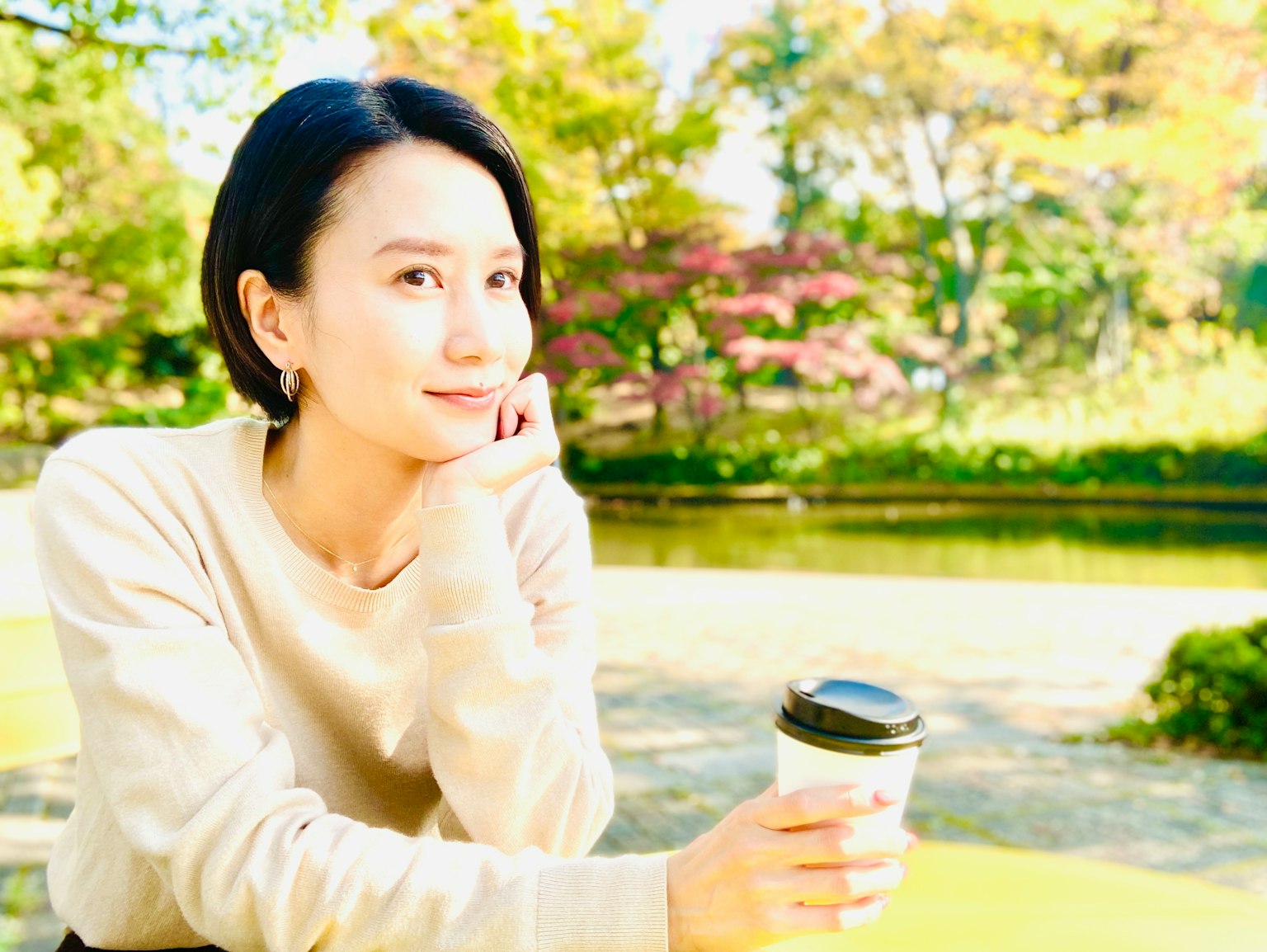 Chân dung một người phụ nữ mỉm cười cầm cà phê trong công viên