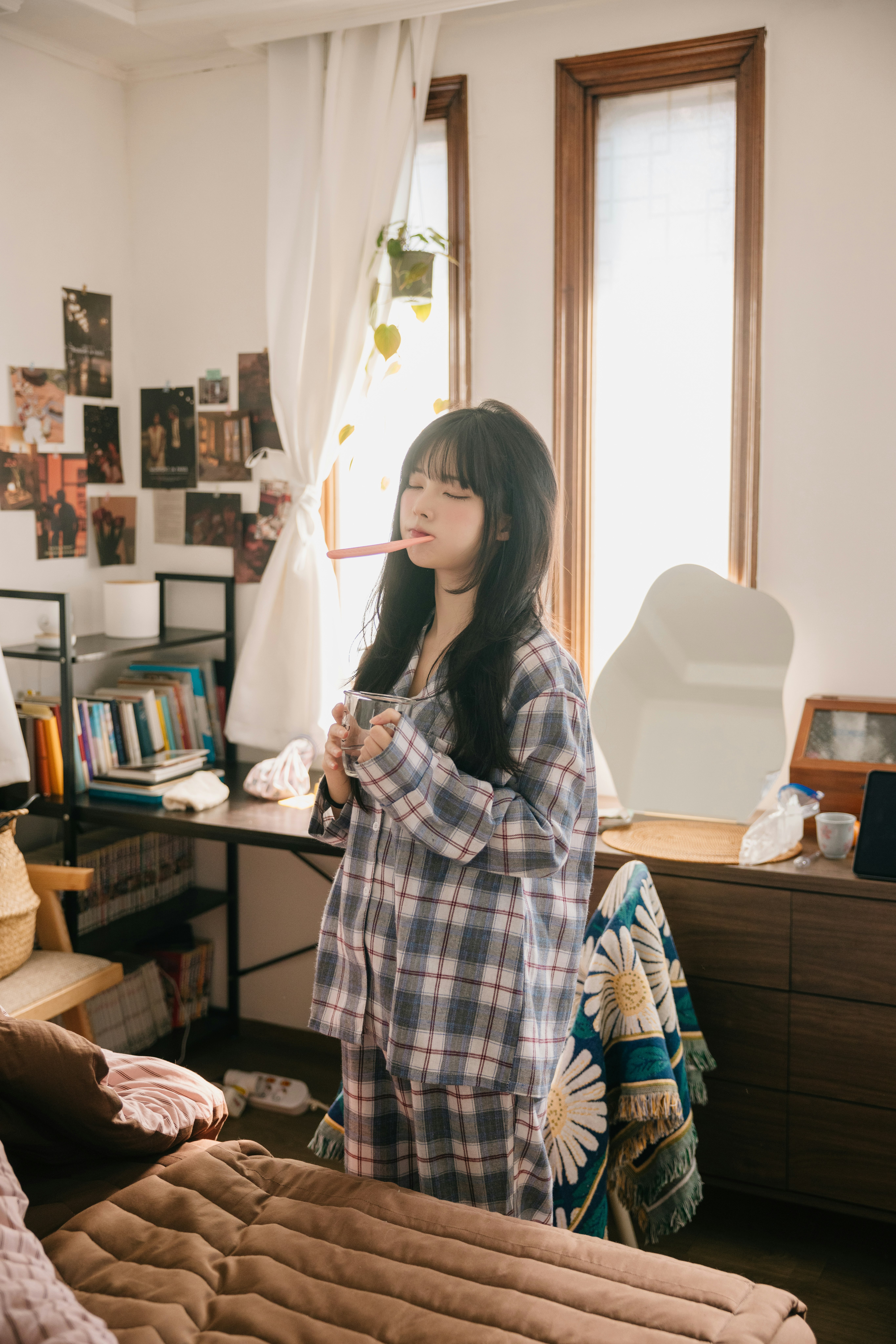 リビングで窓辺に立つチェック柄の女性