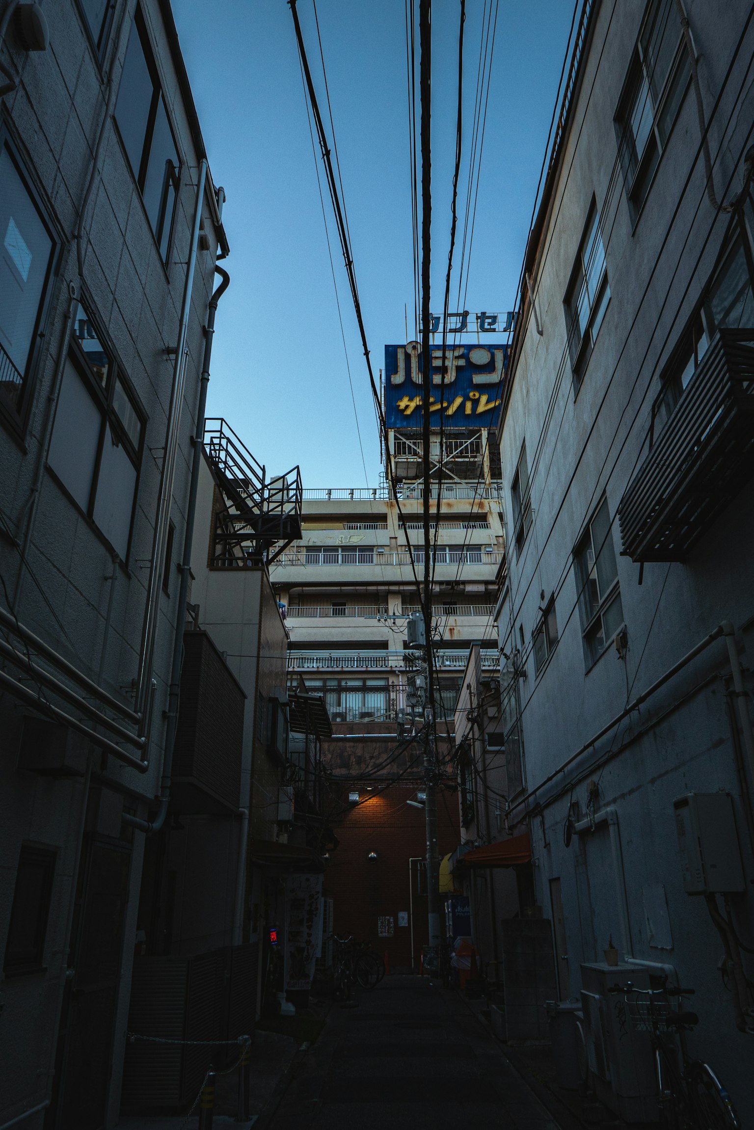 Narrow alley featuring buildings and power lines against a twilight sky