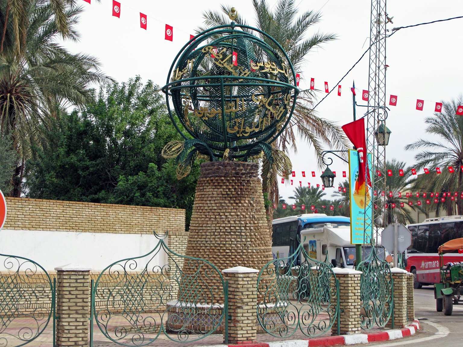 Angolo di strada con un monumento rotondo e palme