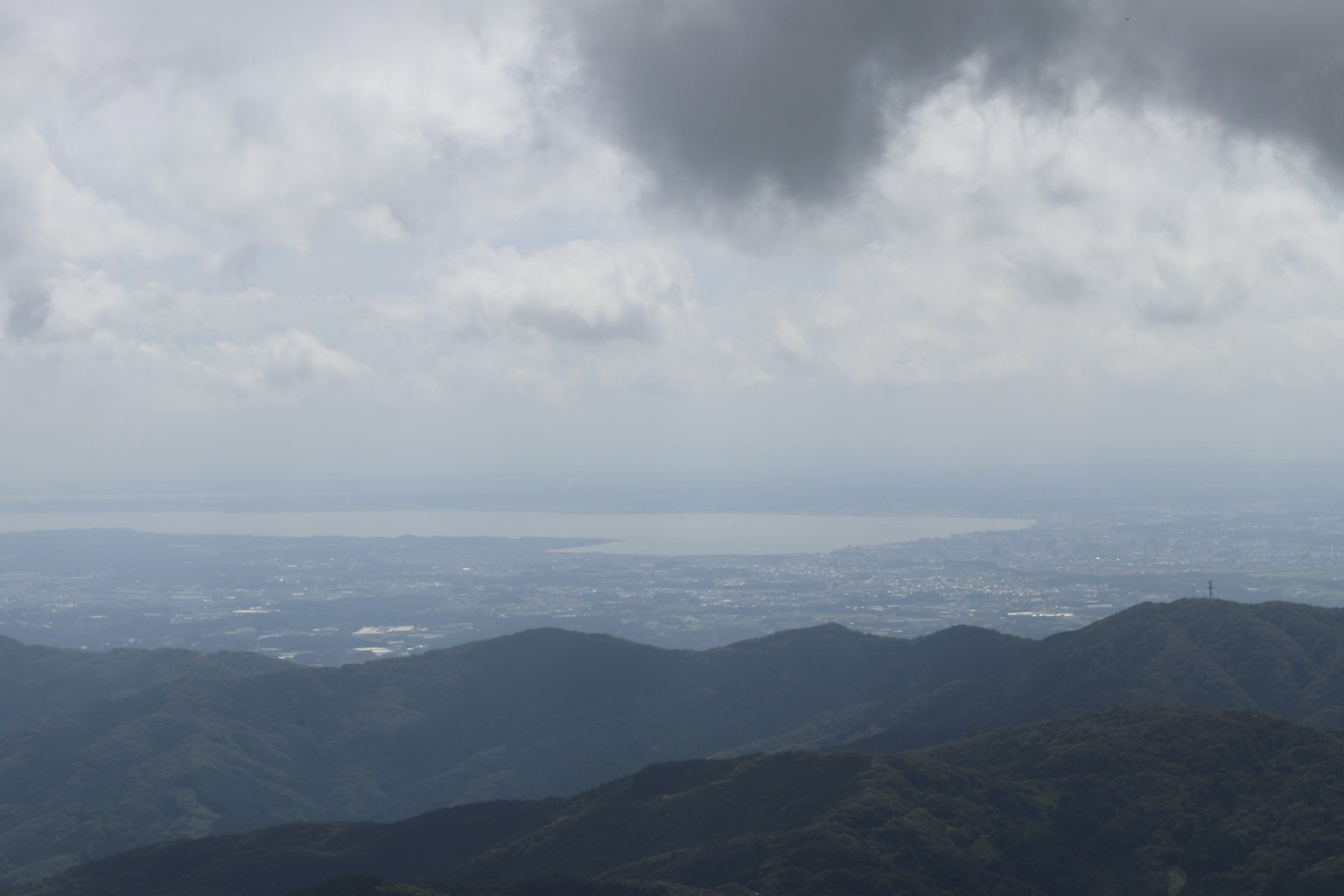 Pemandangan dari puncak gunung dengan langit mendung dan laut yang jauh