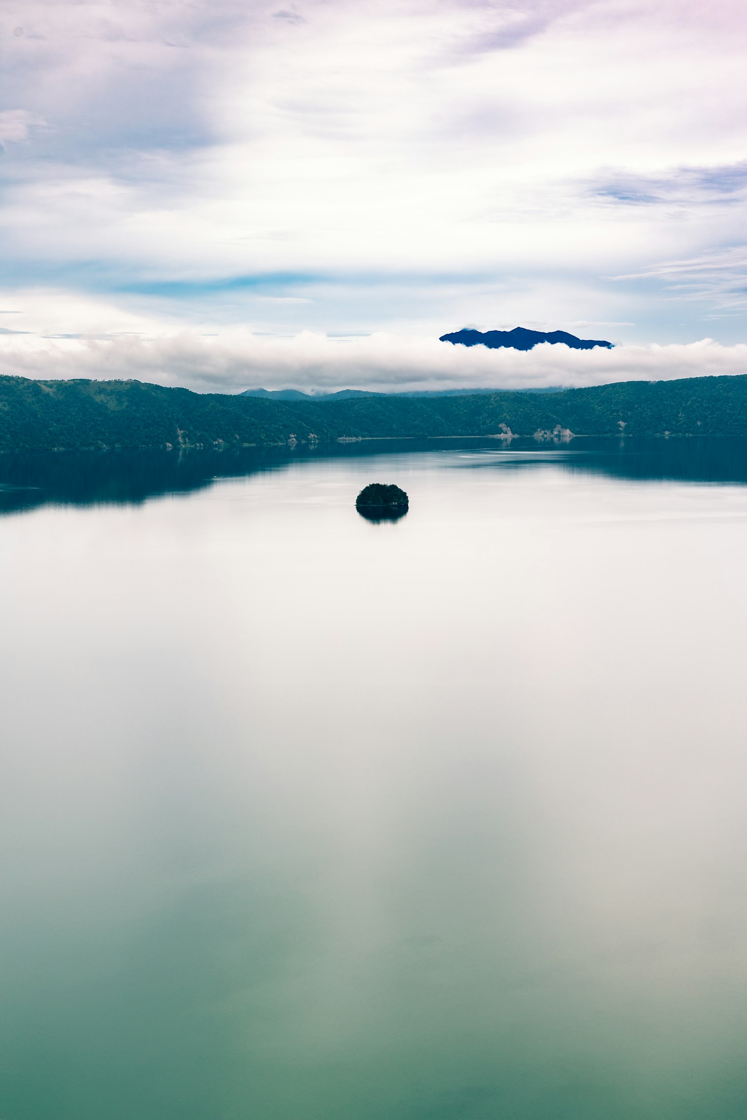 Une surface de lac tranquille avec une petite île et un ciel bleu
