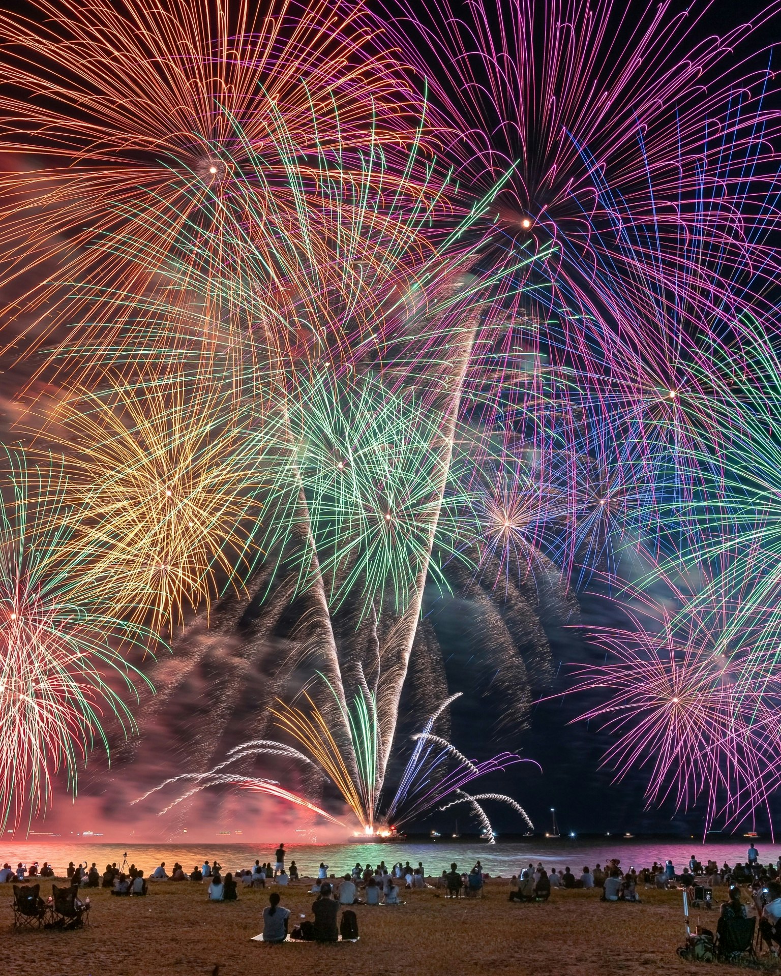 Spectacle de feux d'artifice colorés sur la plage avec des spectateurs