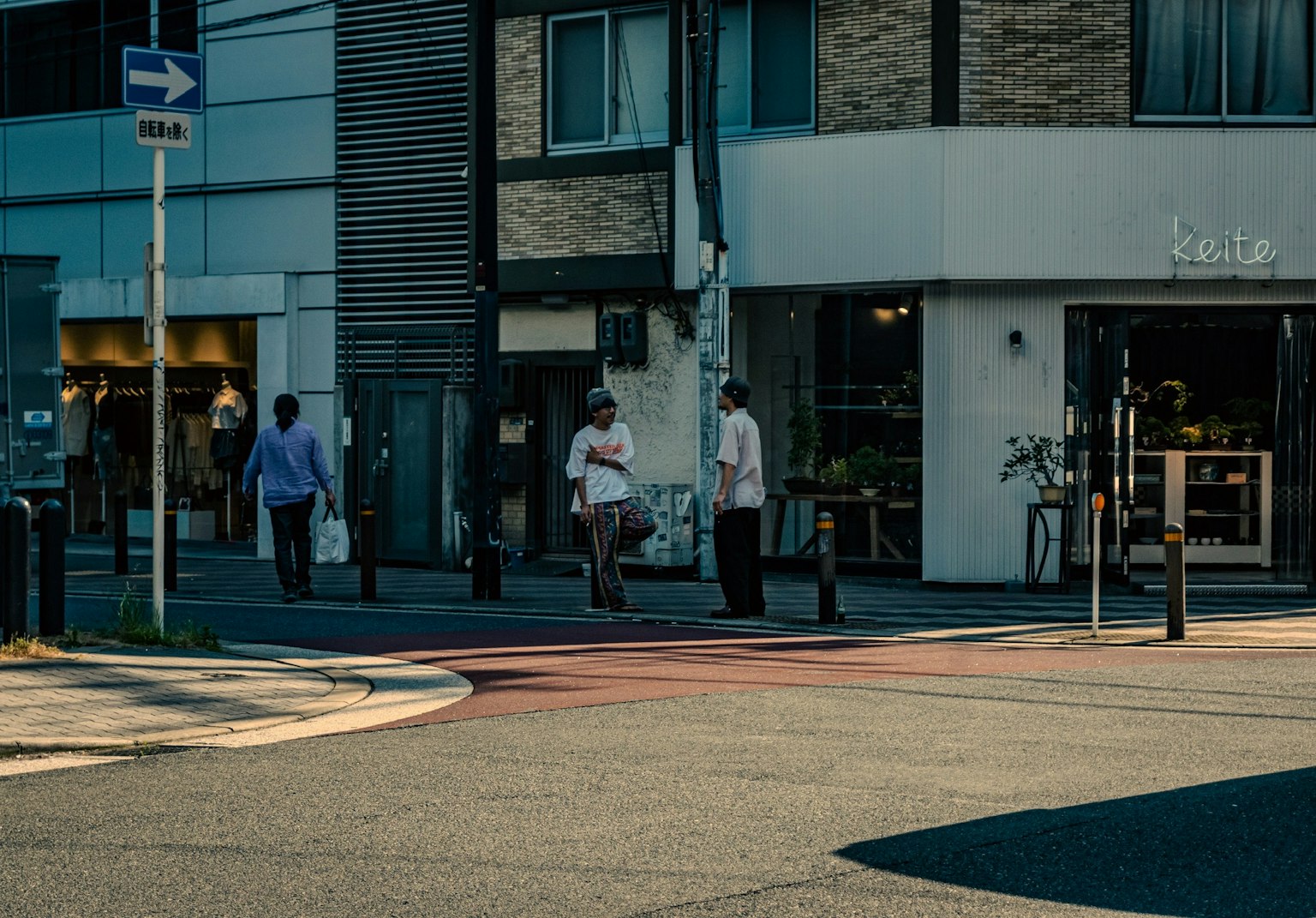 Orang-orang menyeberang di persimpangan di sudut jalan dengan tanda kafe yang terlihat