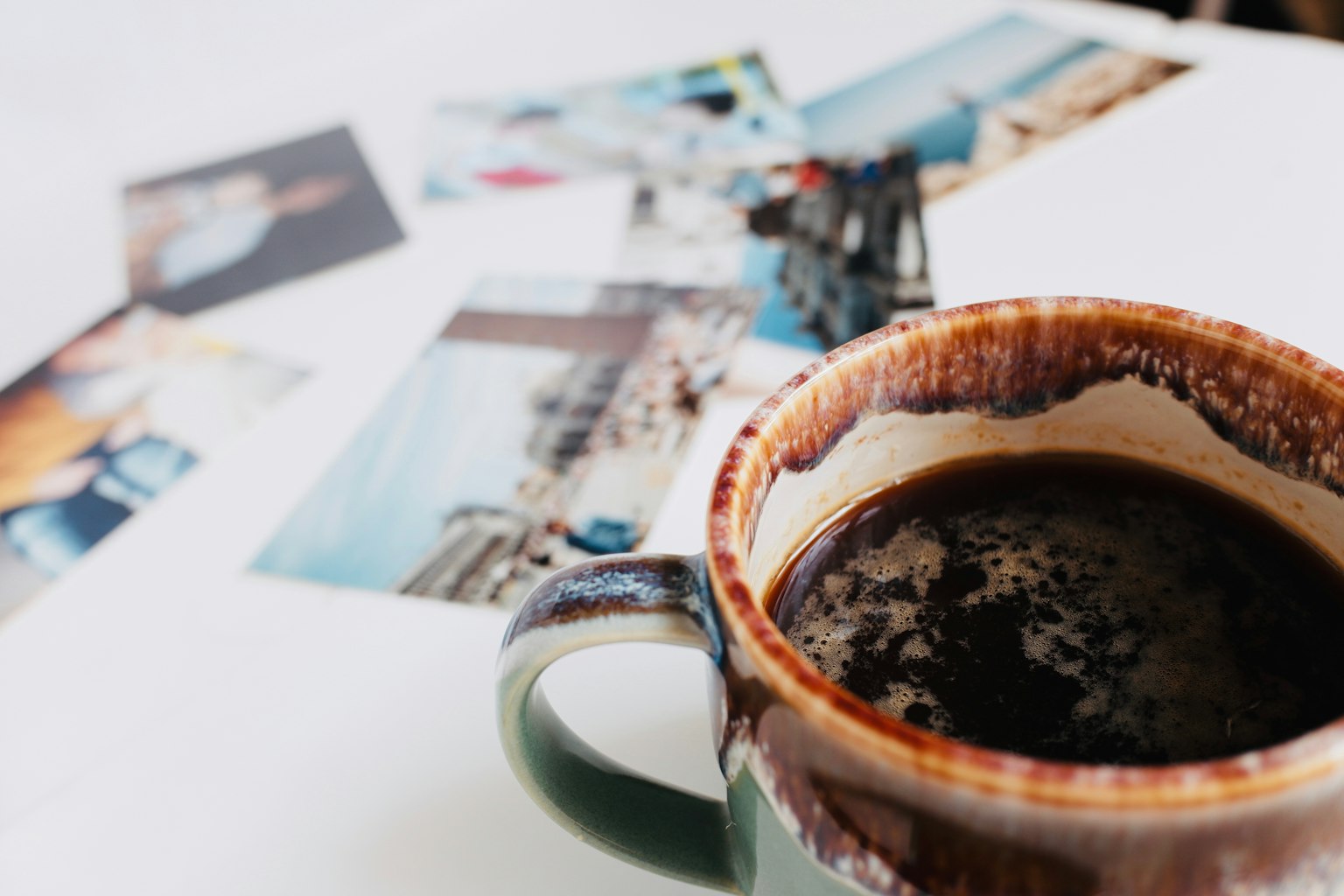ถ้วยกาแฟกับภาพถ่ายที่กระจัดกระจายอยู่บนโต๊ะ