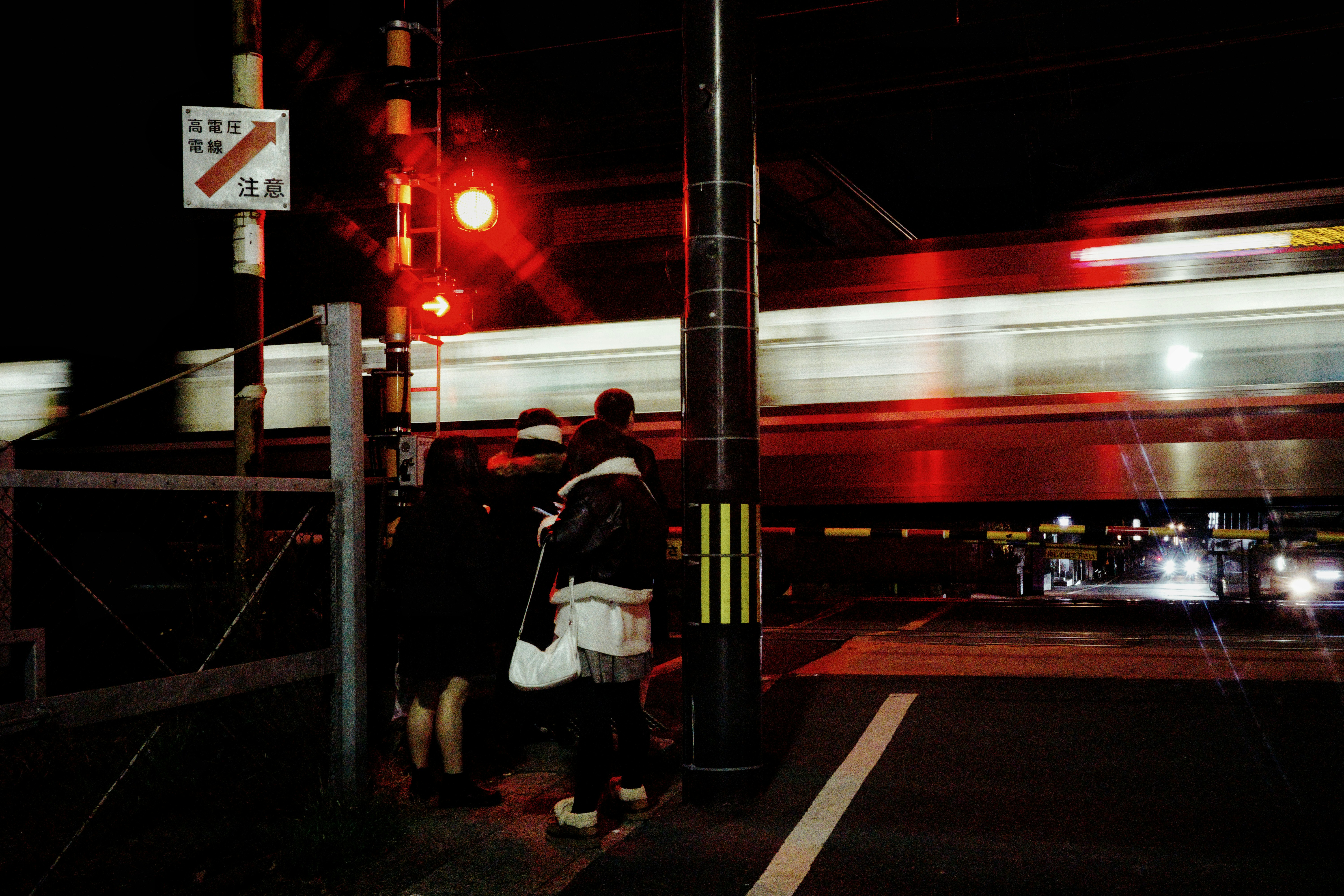 京都夜間鐵路道口，駛過列車的光軌與剪影