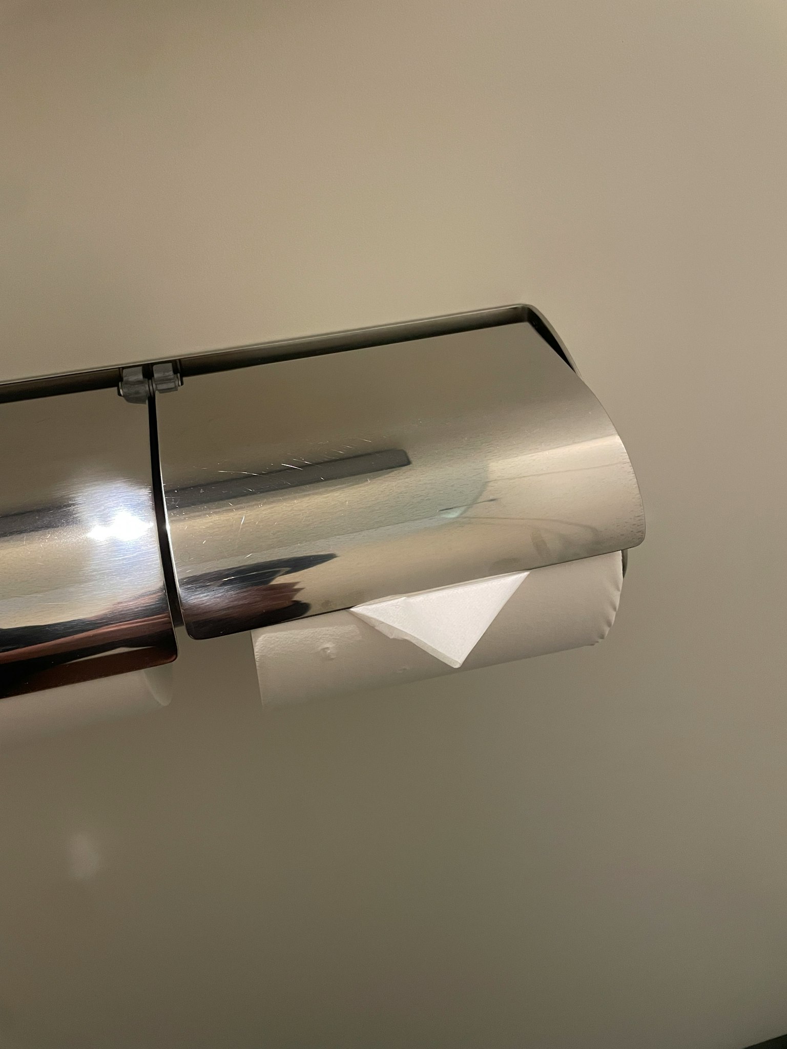 Tempat tisu toilet dari metal dengan sebagian tisu toilet terlihat