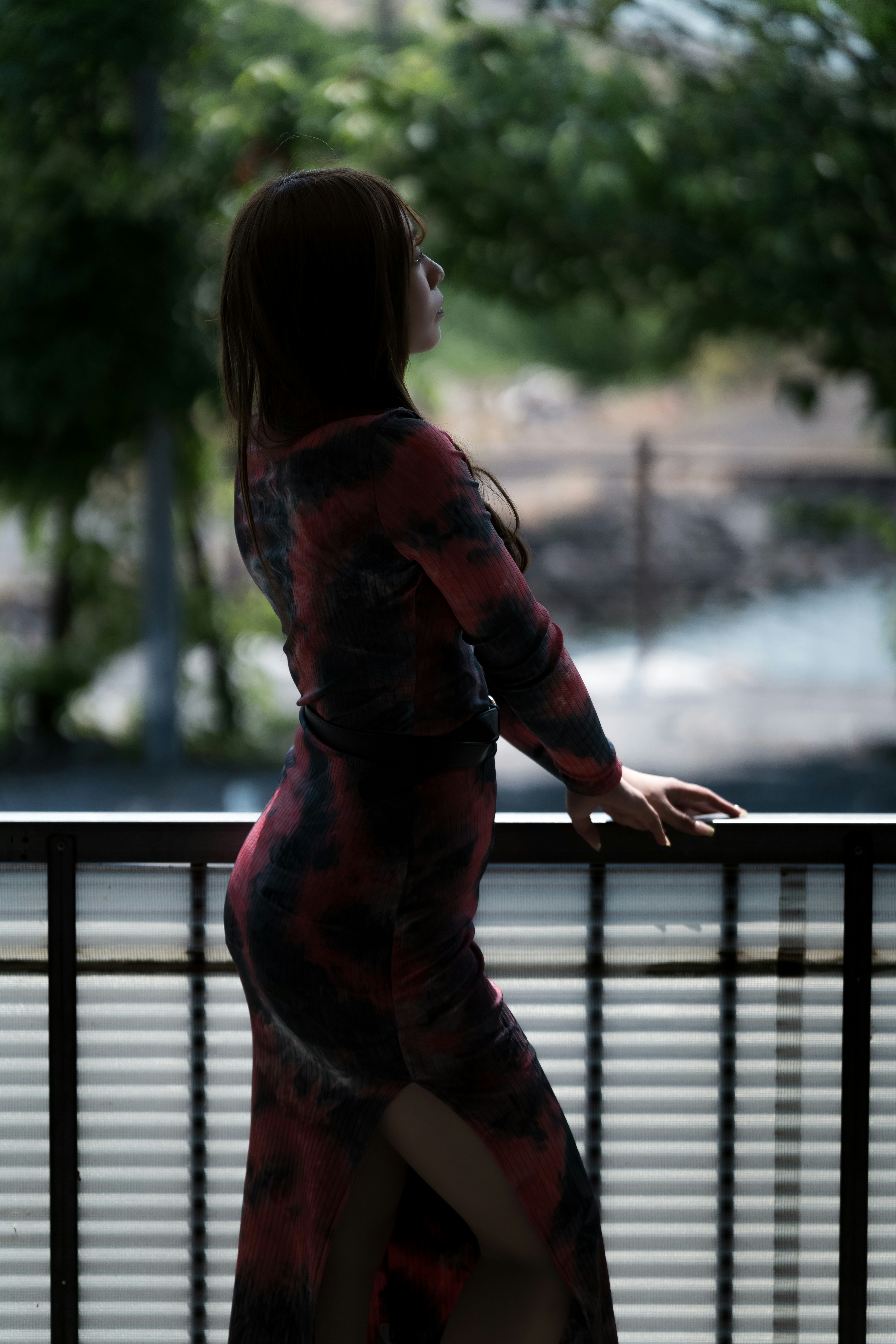手すりにもたれて遠くを見つめる女性の後ろ姿