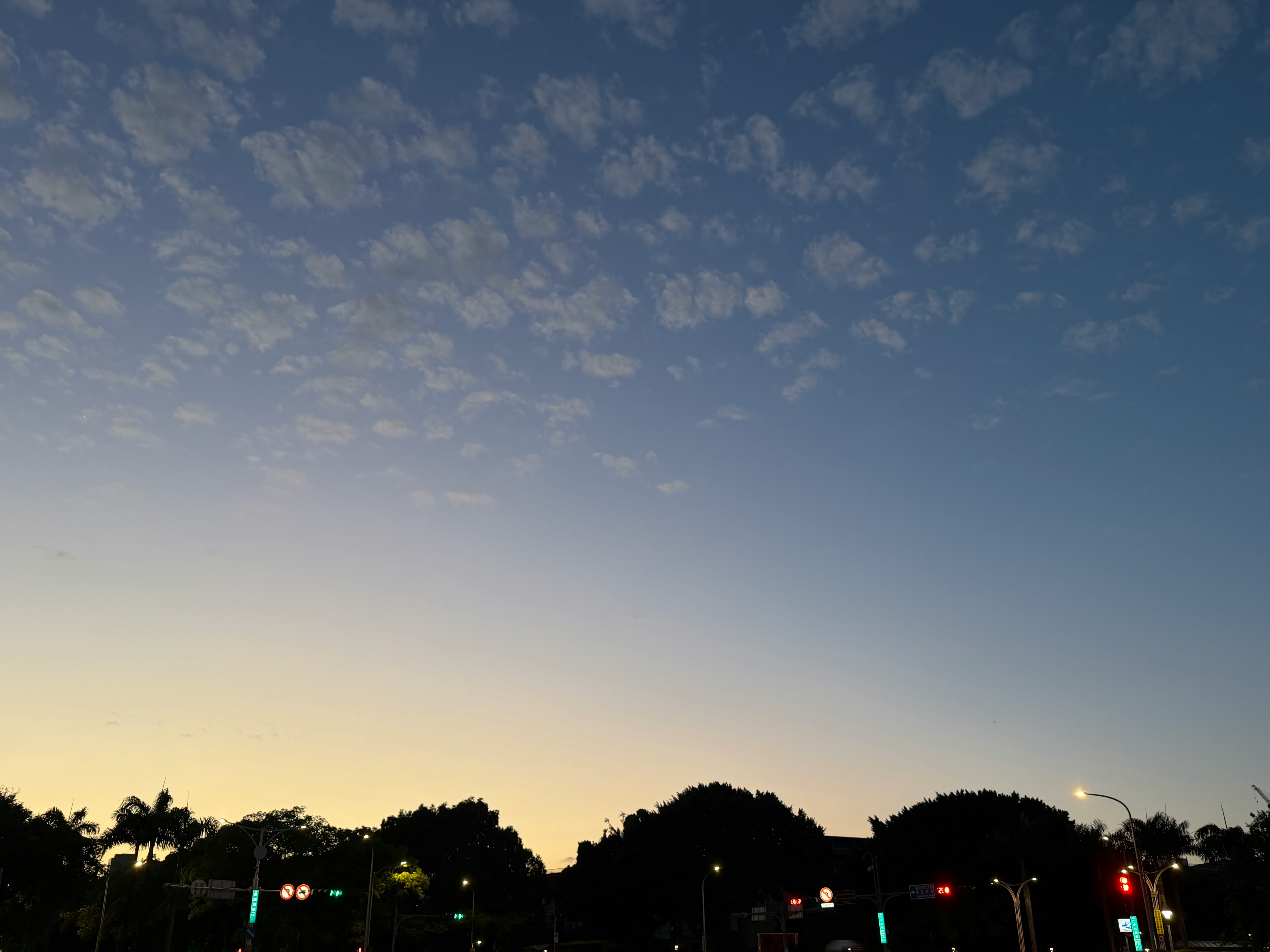 夕暮れの街並みと街灯の光がにじむ空