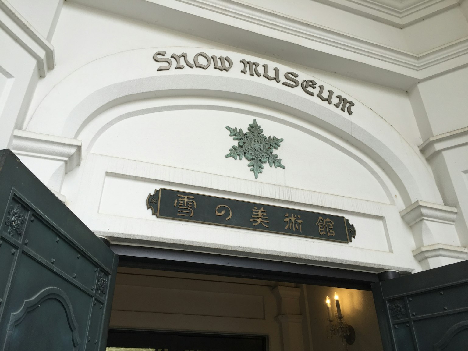 Entrée du musée de la neige avec une décoration en forme de flocon de neige et le nom affiché en anglais et en japonais