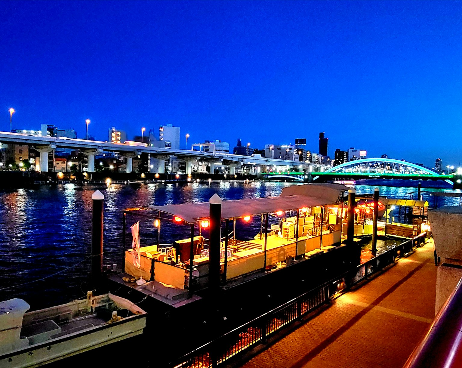 ทิวทัศน์ยามค่ำคืนของเรือร้านอาหารริมแม่น้ำและสะพาน