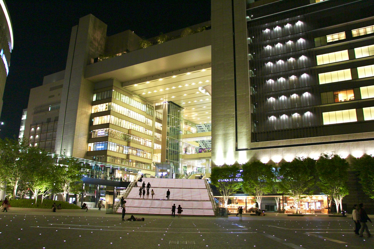 Vista exterior de un edificio moderno por la noche con personas