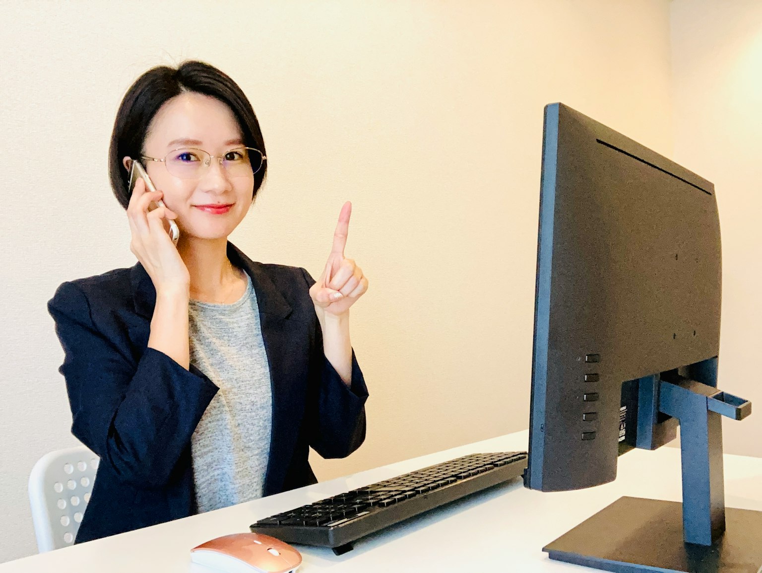 Wanita berbicara di telepon sambil menunjuk ke komputer