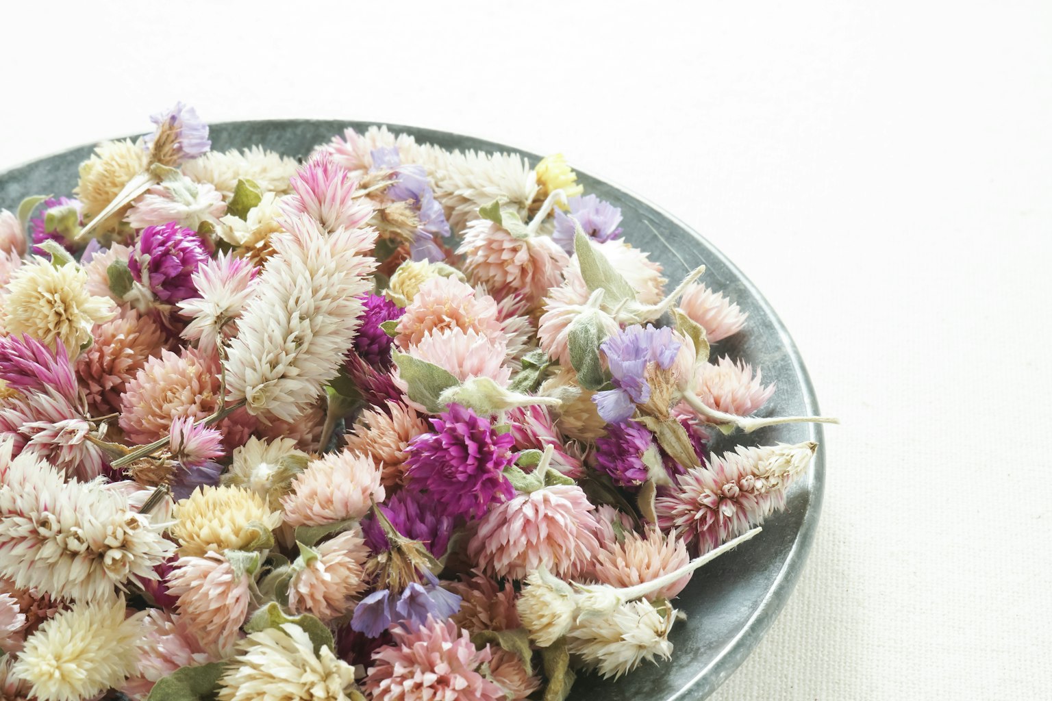 Fleurs séchées colorées disposées dans une assiette noire