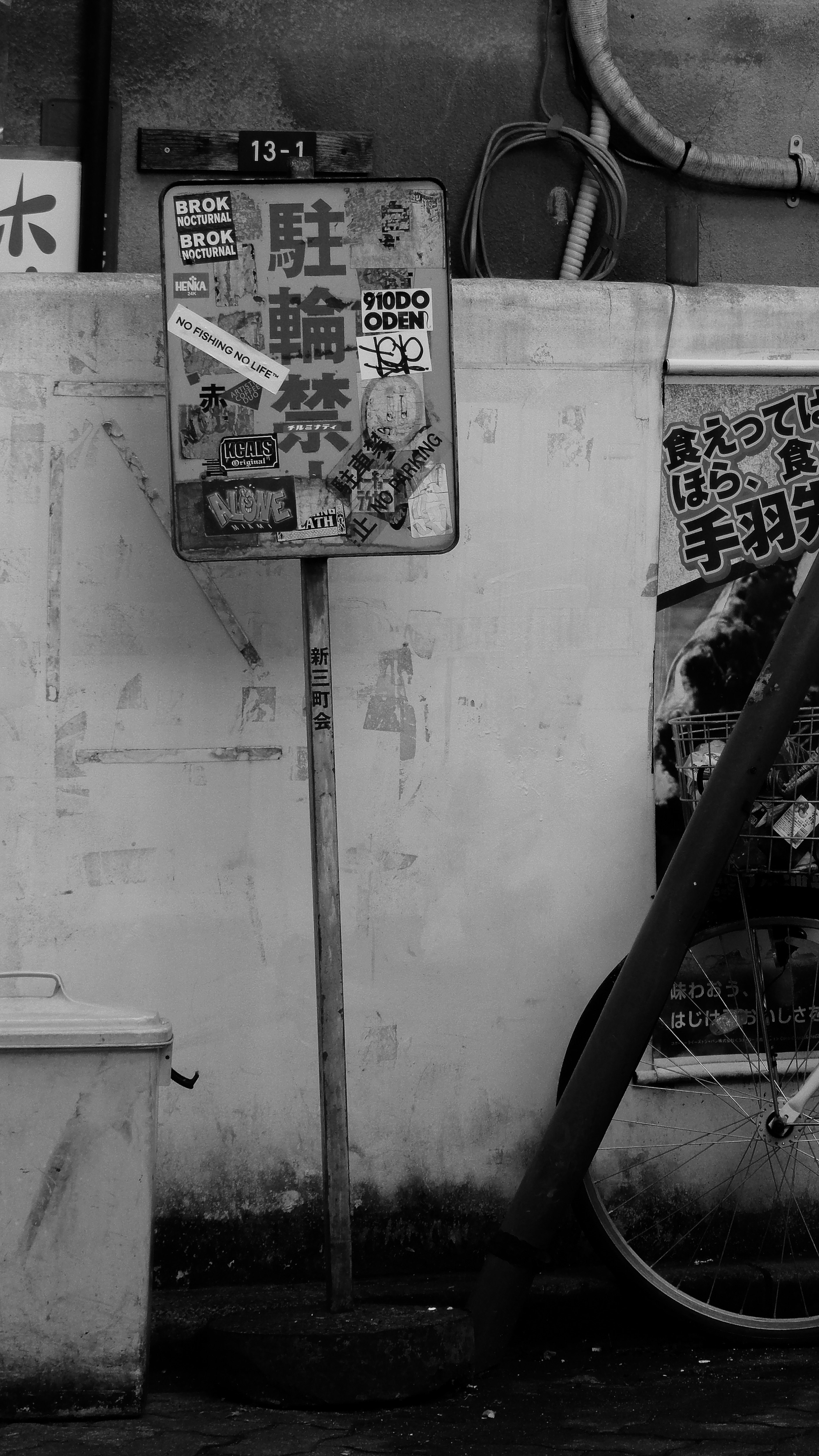 vélos et panneaux collés sur le mur d’une ruelle