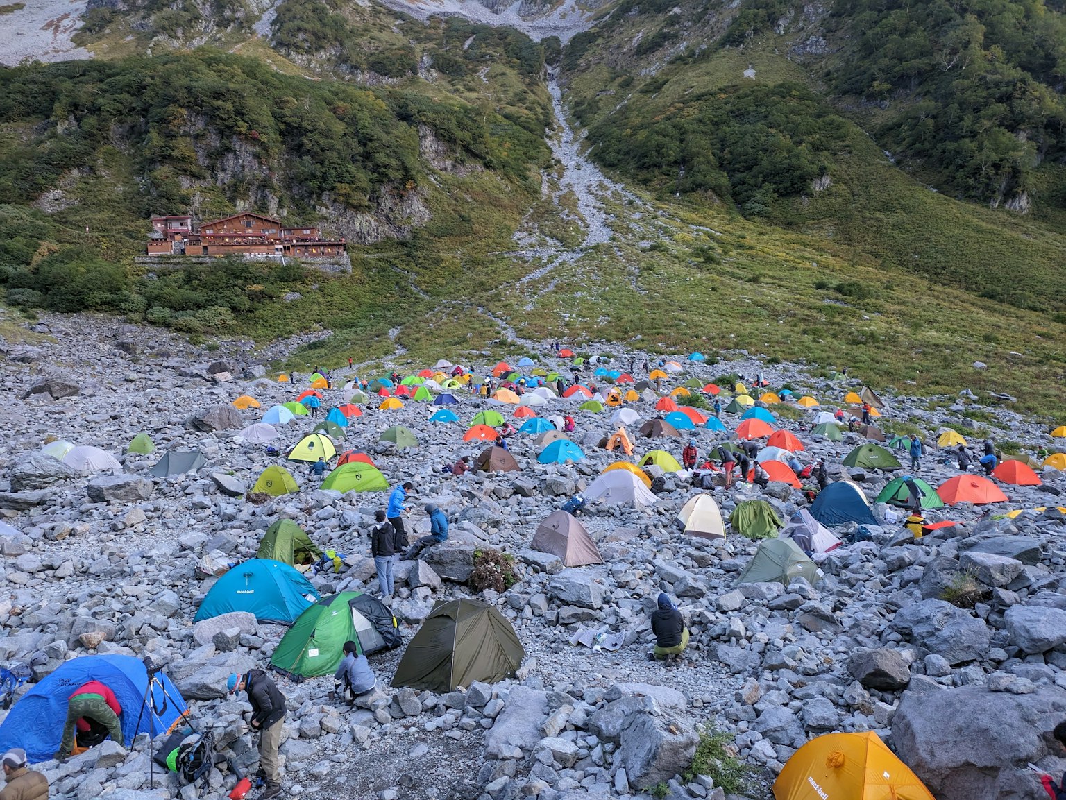 一幅多彩帐篷分布在岩石山坡上的景象