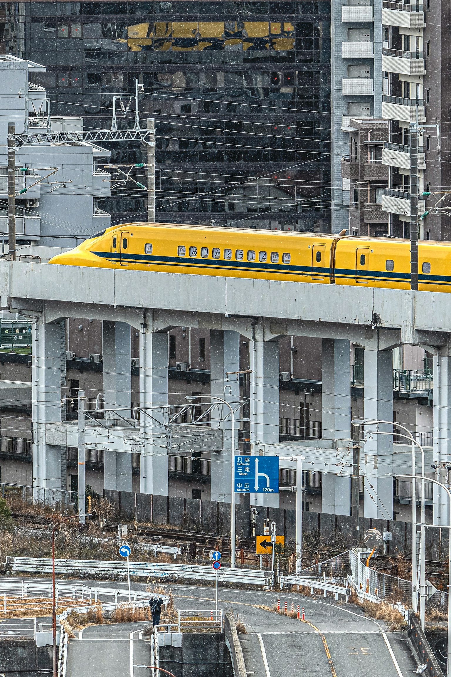 รถไฟชิงกันเซนสีเหลืองบนรางสูงในสภาพแวดล้อมในเมือง