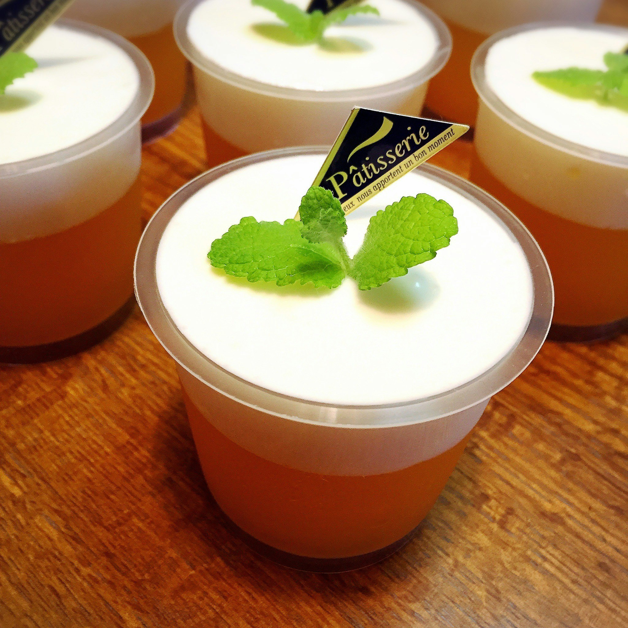 ミントの葉をのせたカップ入りデザートとカラメル色の飲み物